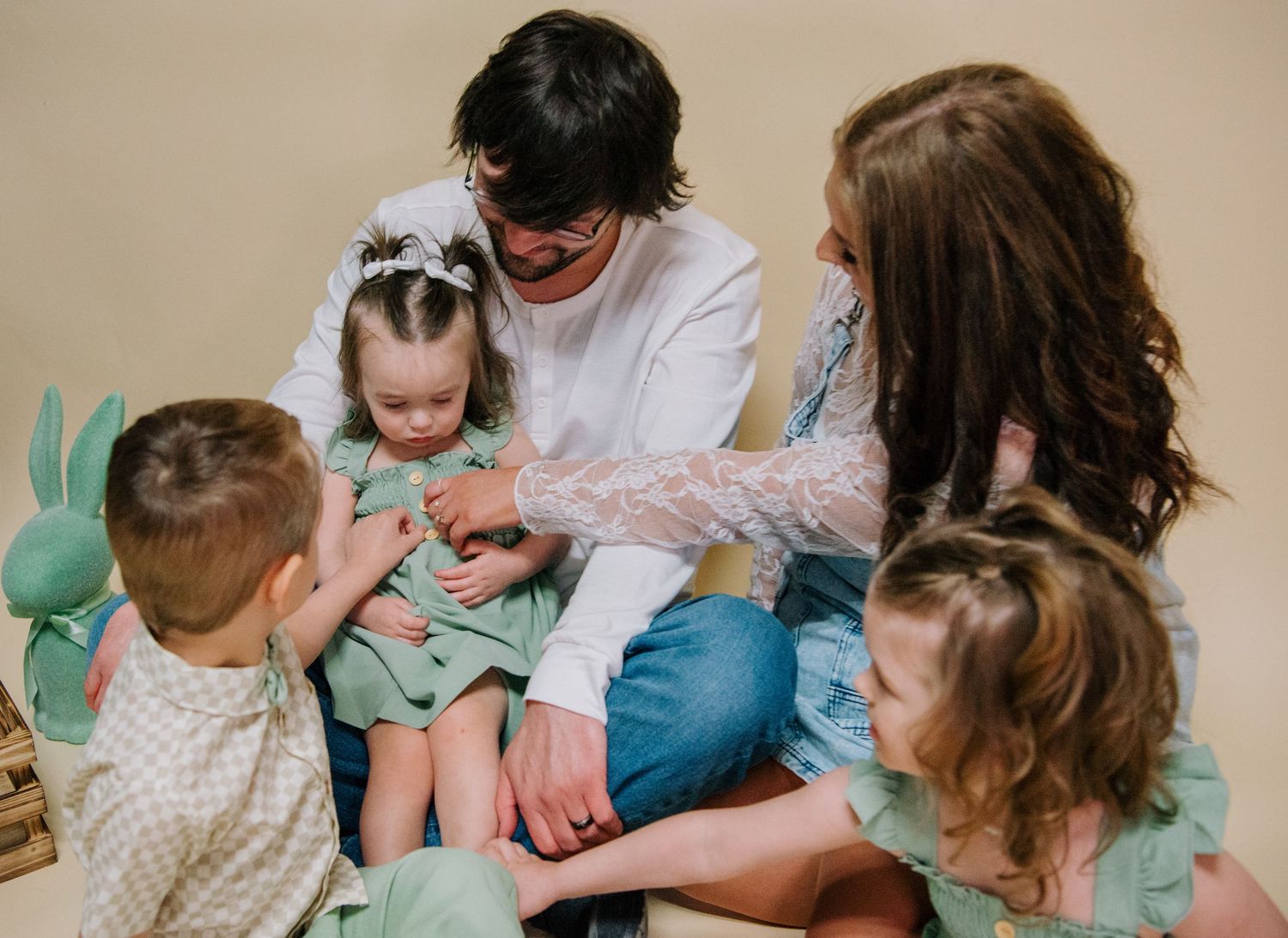 A group sits together on the floor during a tender family moment in a room with beige walls and decor.