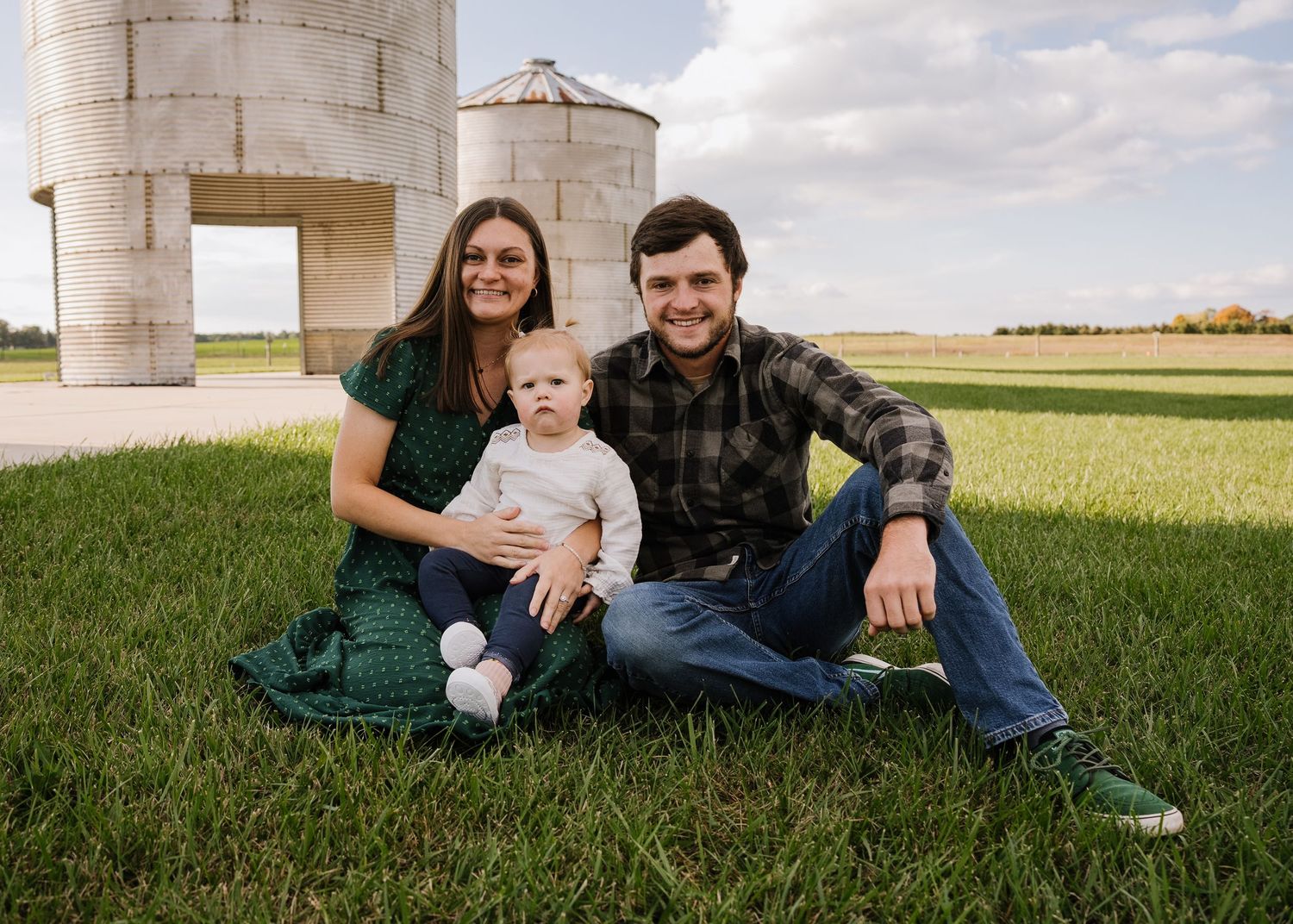 A series of five outdoor family photos showing people sitting together in grassy fields on a sunny day.