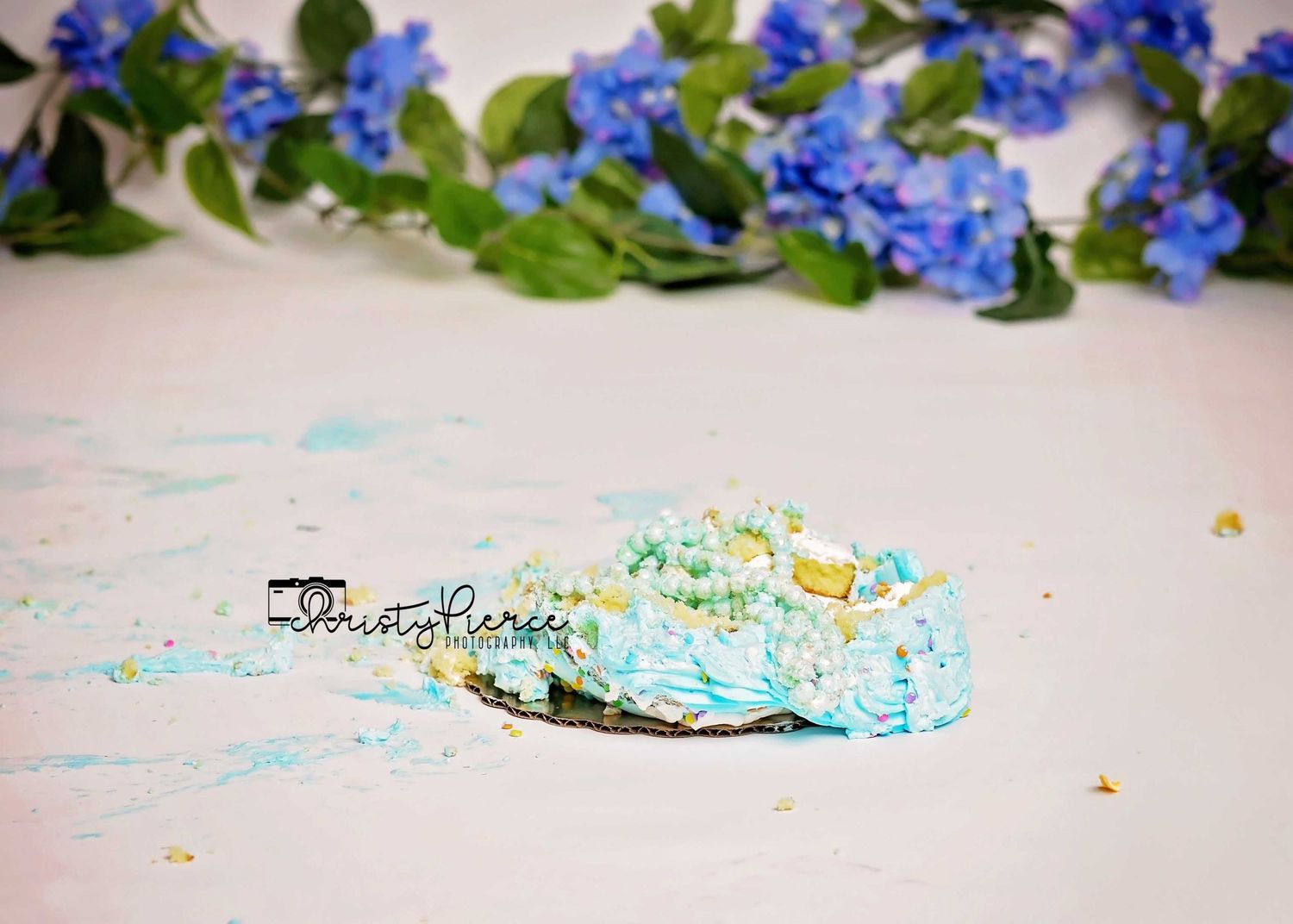 A decorative border made of vibrant blue forget-me-not flowers and green leaves arranged on a light background.