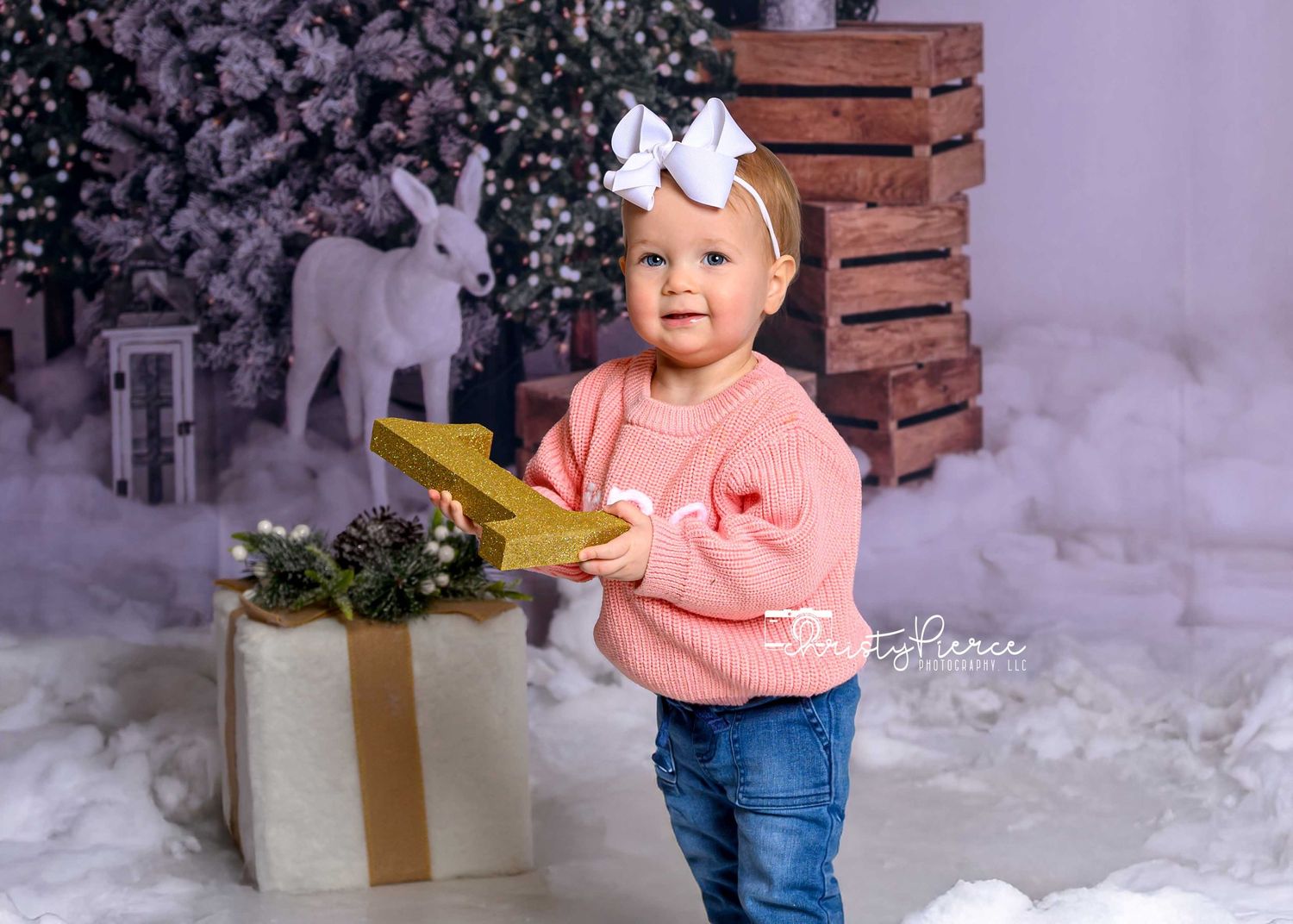 A child in a pink sweater and jeans plays with a stuffed polar bear in a winter wonderland setting.
