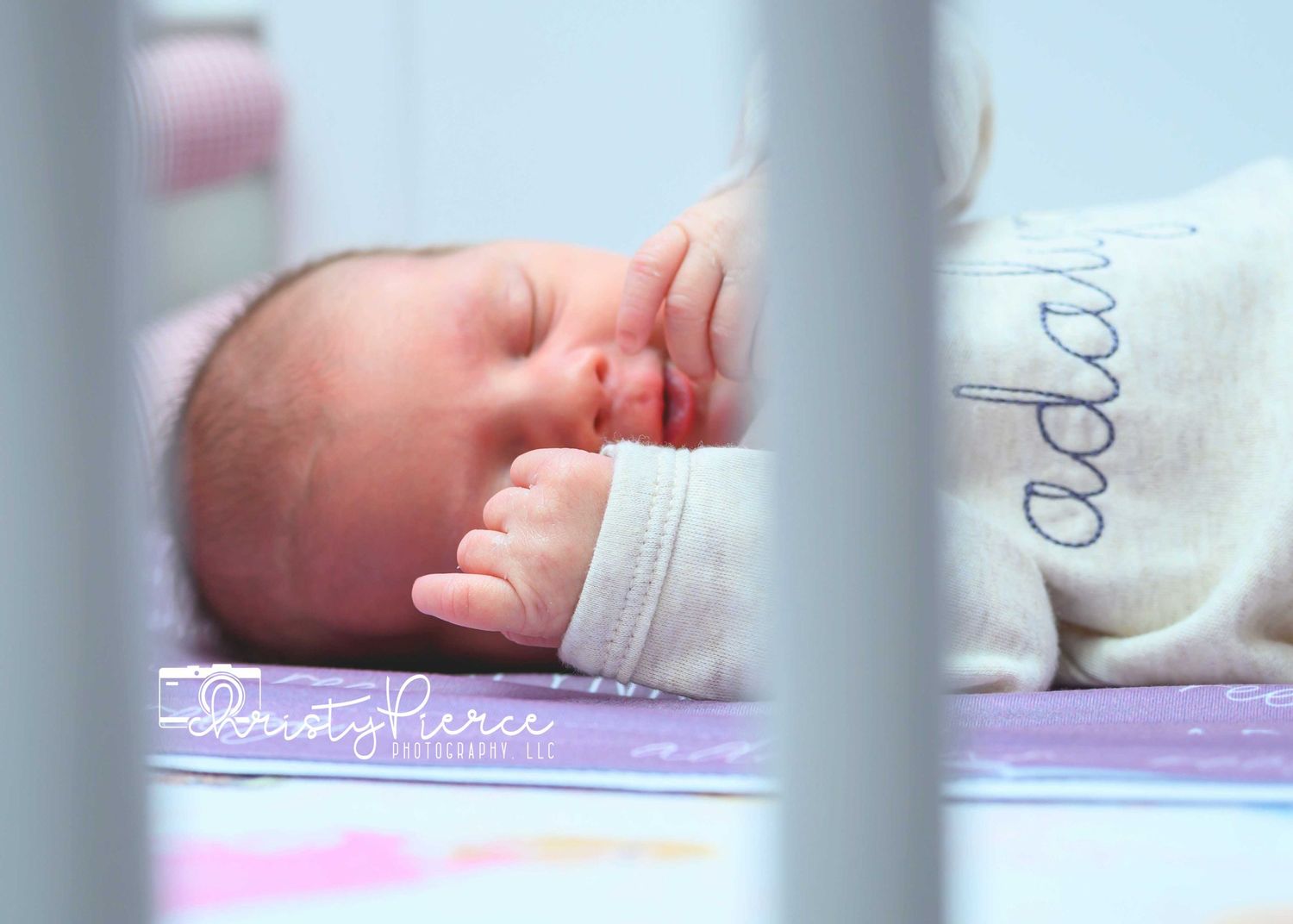 Close-up view of a sleeping newborn baby through nursery crib bars.