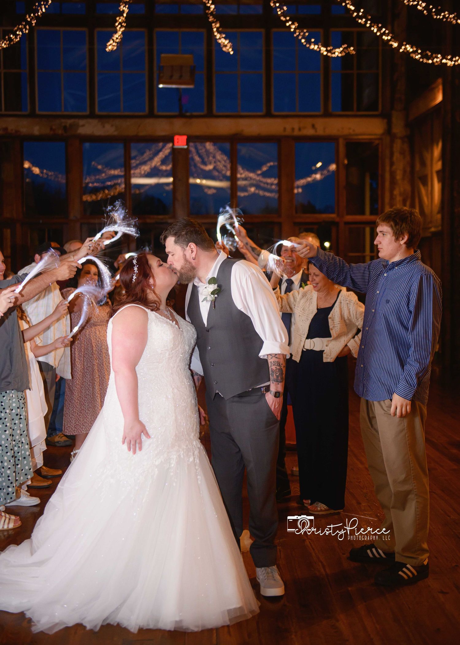 Bride and groom share a kiss during a sparkler send-off at a rustic barn wedding reception.