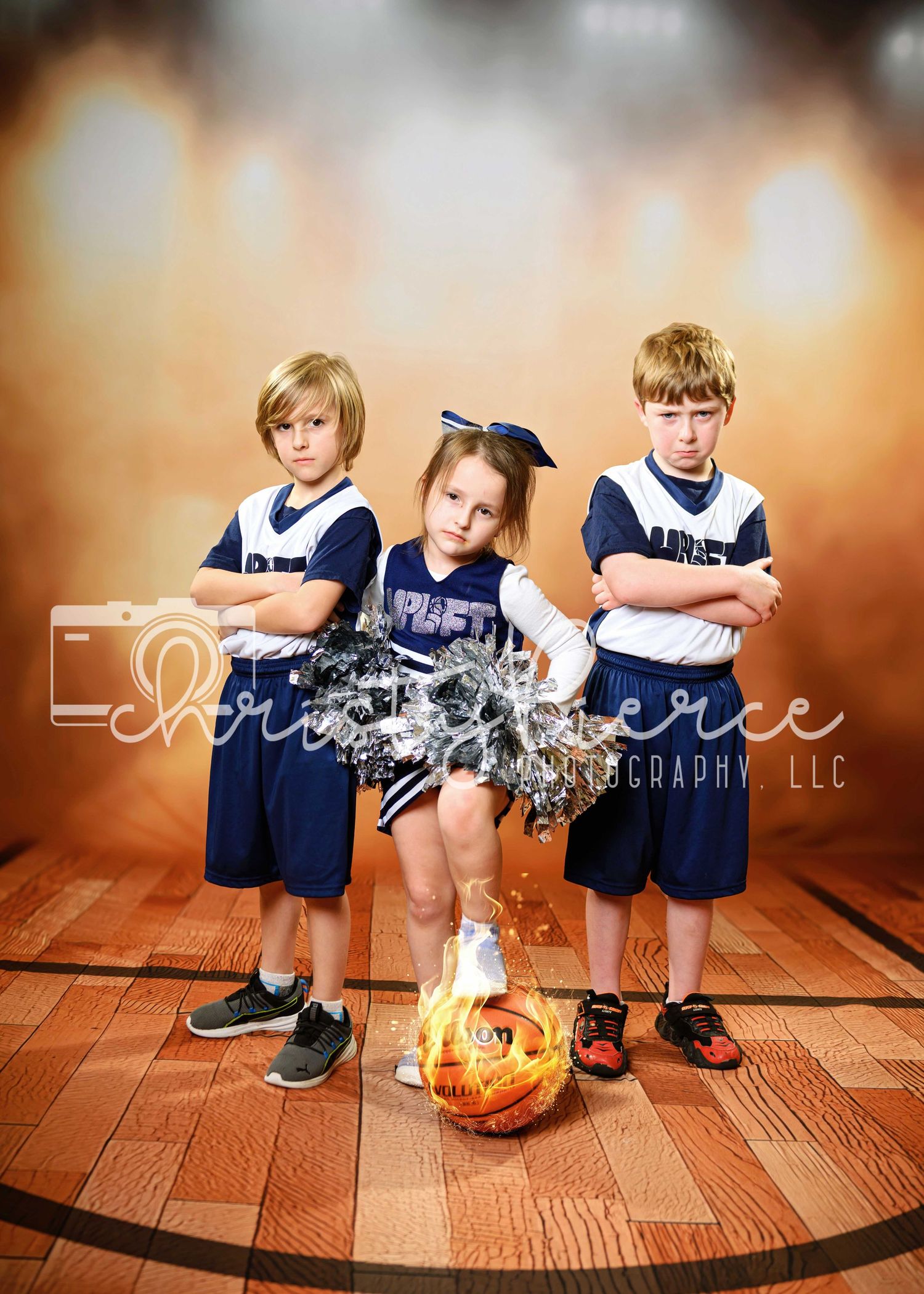 Three children in athletic uniforms pose with a flaming basketball on wooden court.