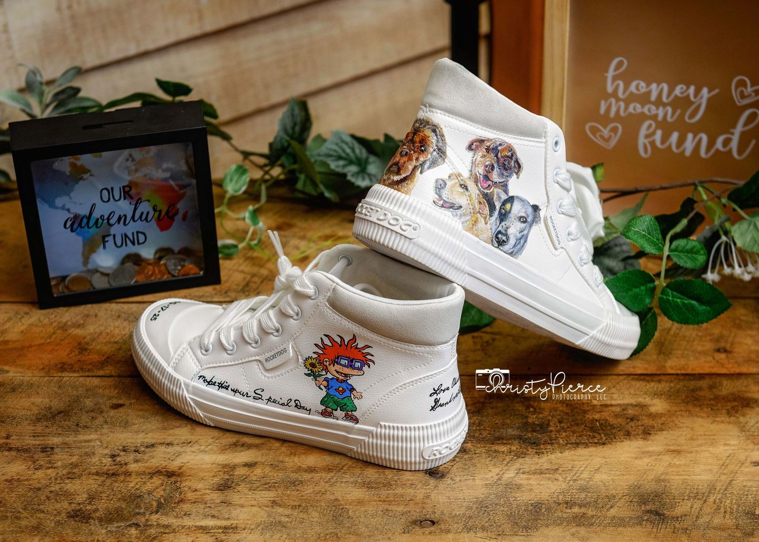 A series of white sneakers with custom hand-painted designs displayed on a rustic wooden surface with decorative elements.