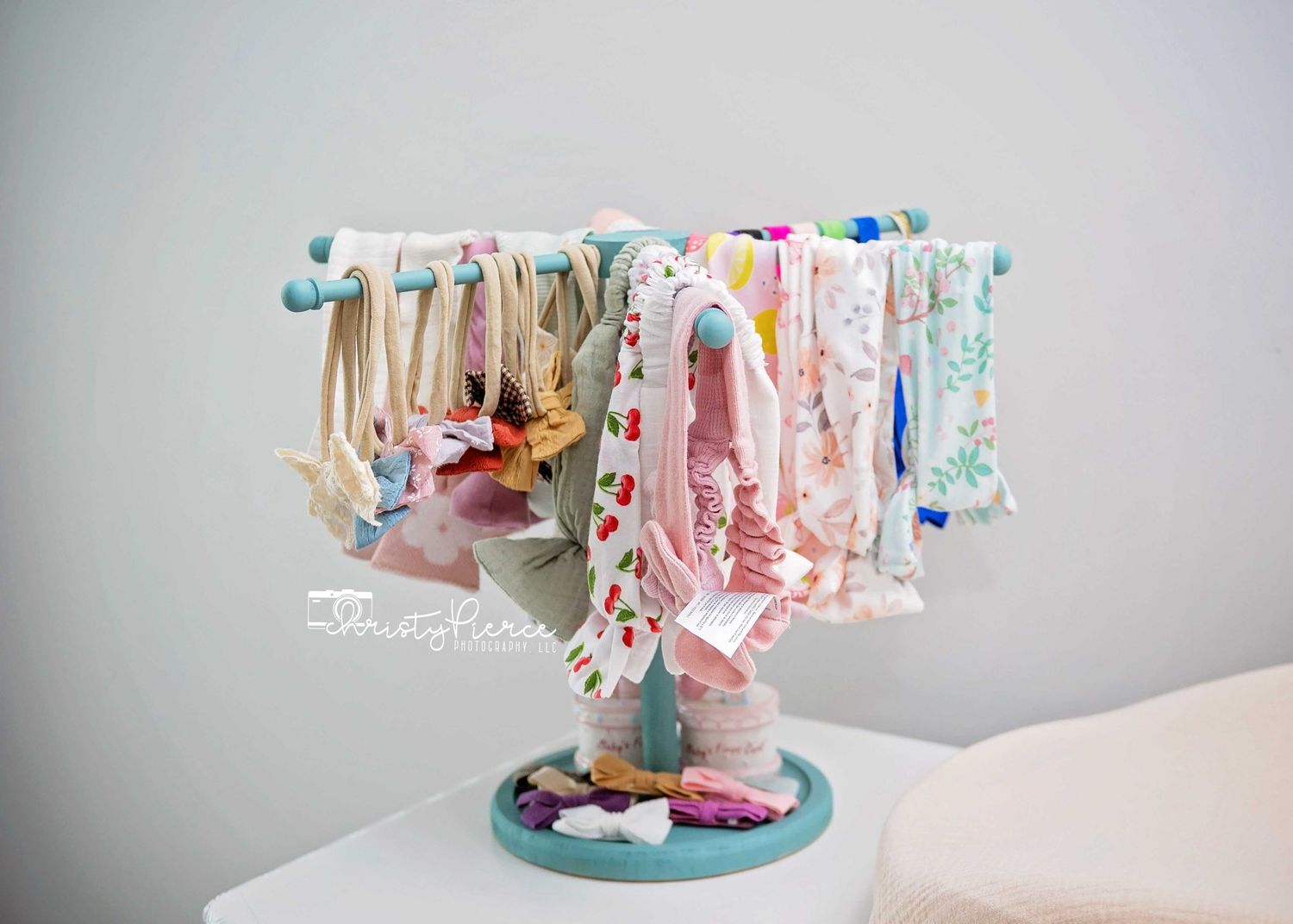 A decorative carousel cake stand with delicate pastel ribbons and clothespins hanging from its circular display edge.