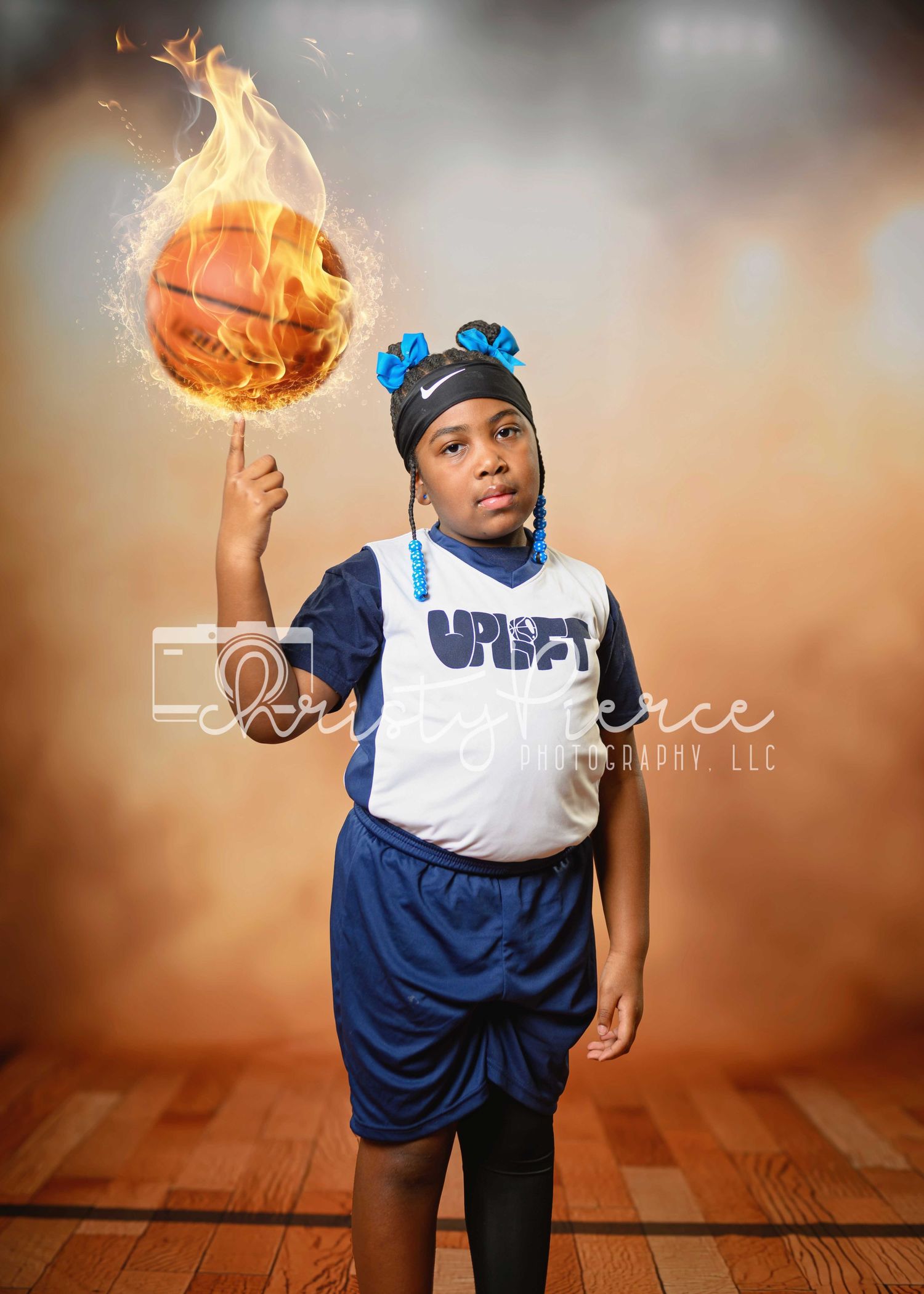 Young basketball player in blue and white uniform spinning a flaming basketball on their finger on a wooden court.