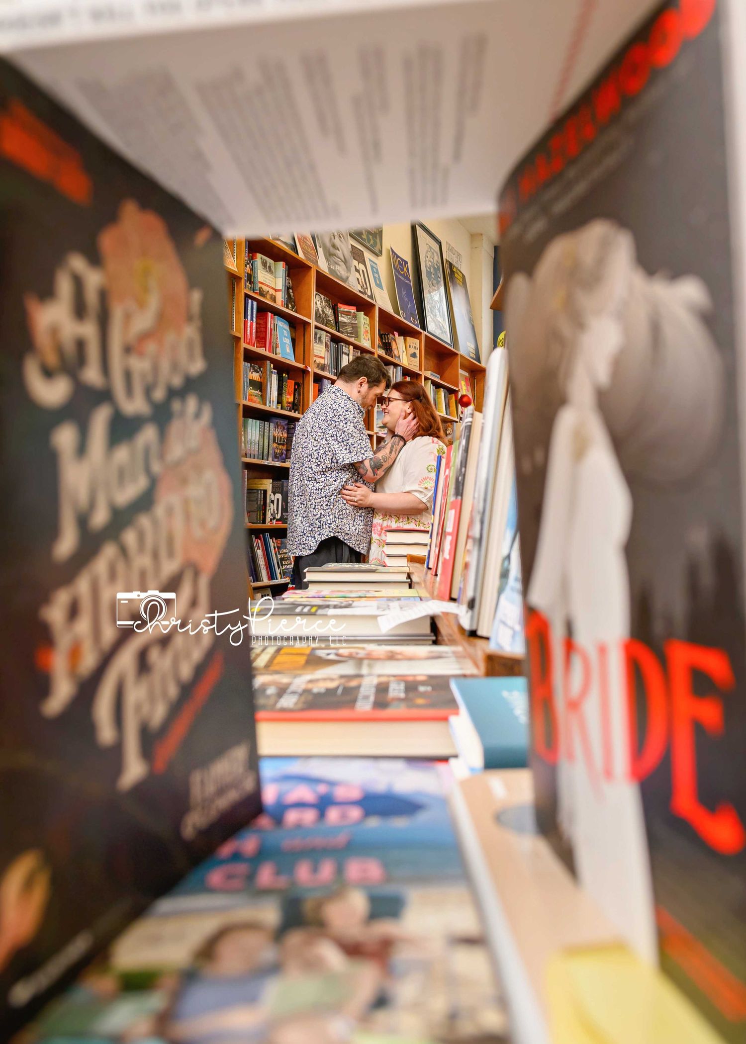 Person browsing through books on shelves at a bookstore with graffiti-style wall art visible in the background.