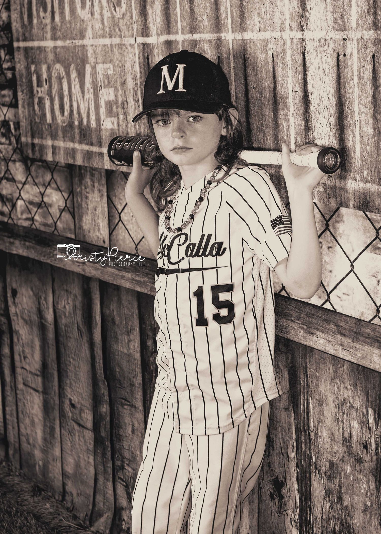 A sepia-toned baseball portrait showing a player in pinstriped uniform with number 15 leaning against a chain-link fence.
