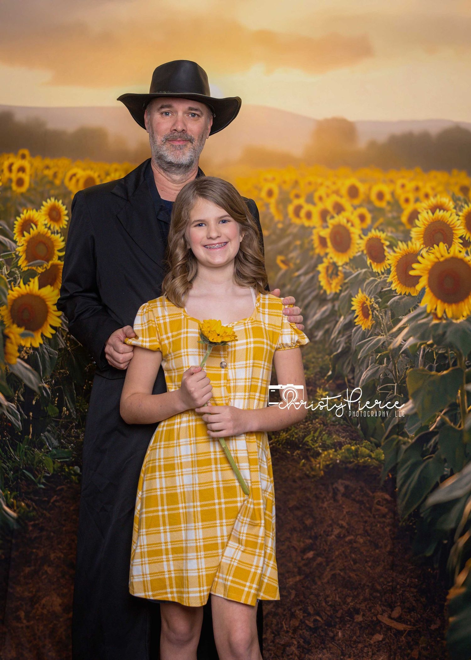 A beautiful sunset portrait in a field of blooming sunflowers with yellow plaid dress and black coat.