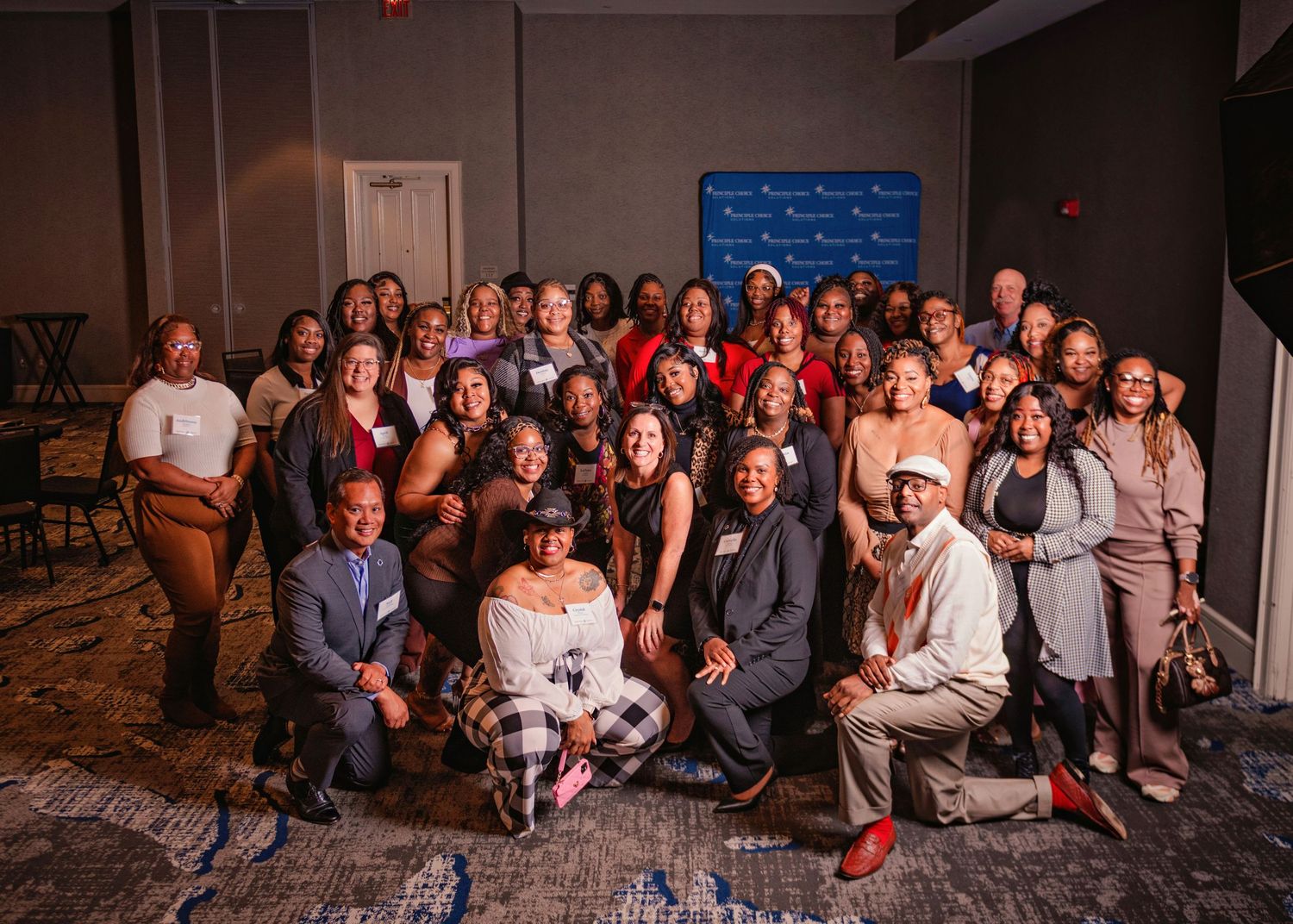 Large group photo of people gathered together in a hotel conference room for a professional event or meeting.