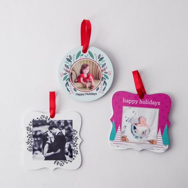 Collection of decorative holiday photo ornaments with red ribbons arranged in a row on white background.