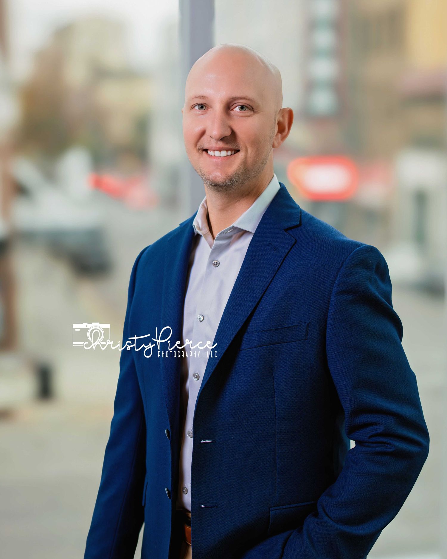 Professional headshot portrait series showing a man in a navy suit and tie against a blurred urban background.