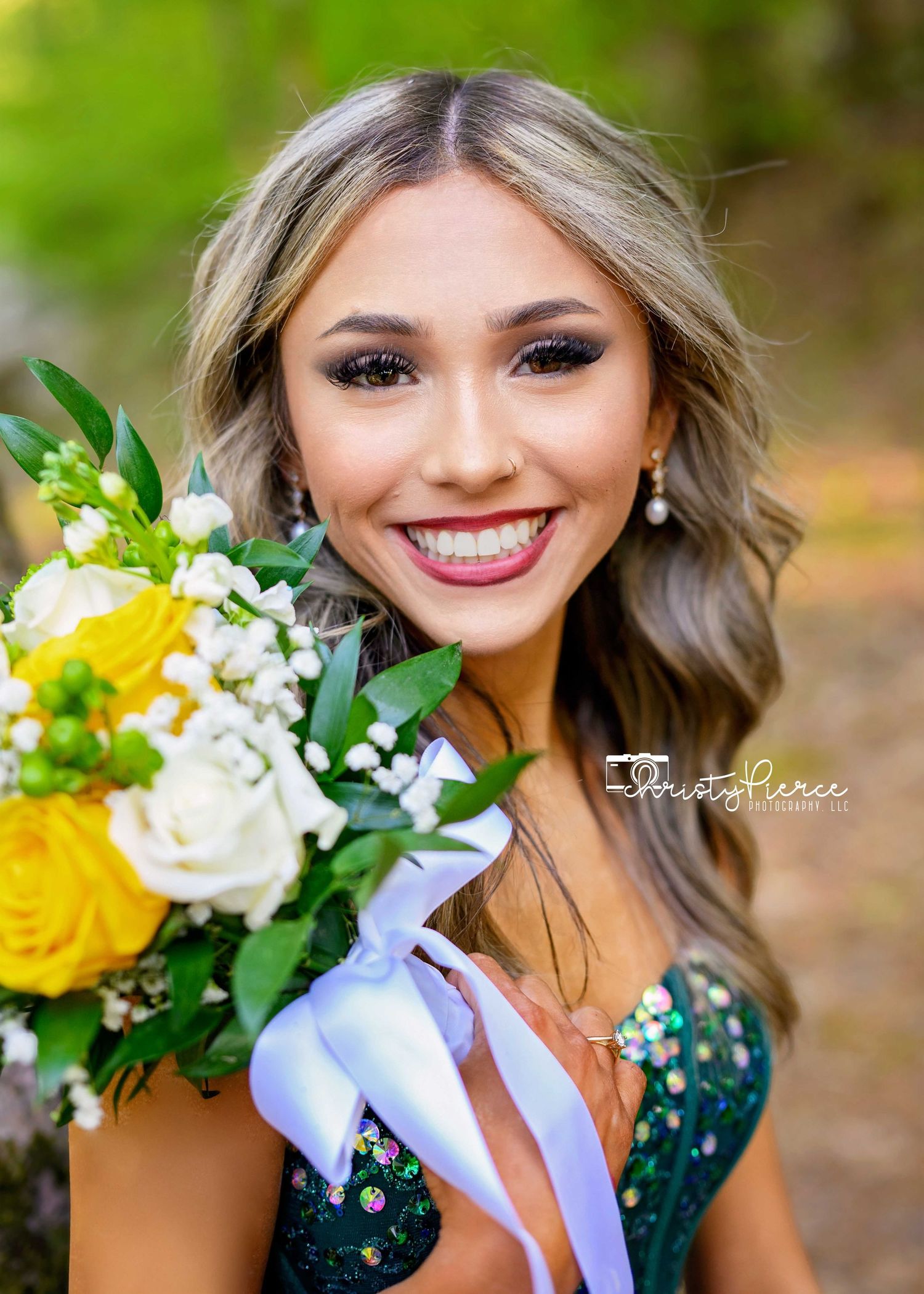 Elegant floral bouquet with yellow roses and white flowers held against a dark green formal dress.