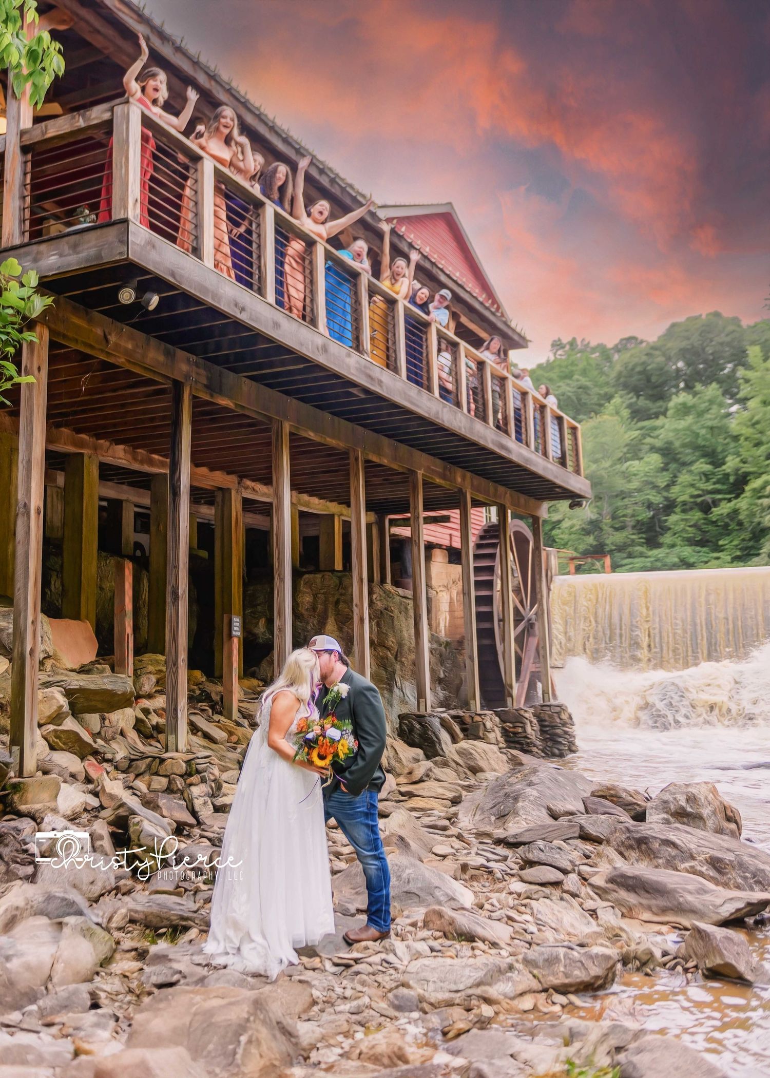 Rustic waterfall wedding venue with wooden deck balcony and dramatic sunset sky in the background.