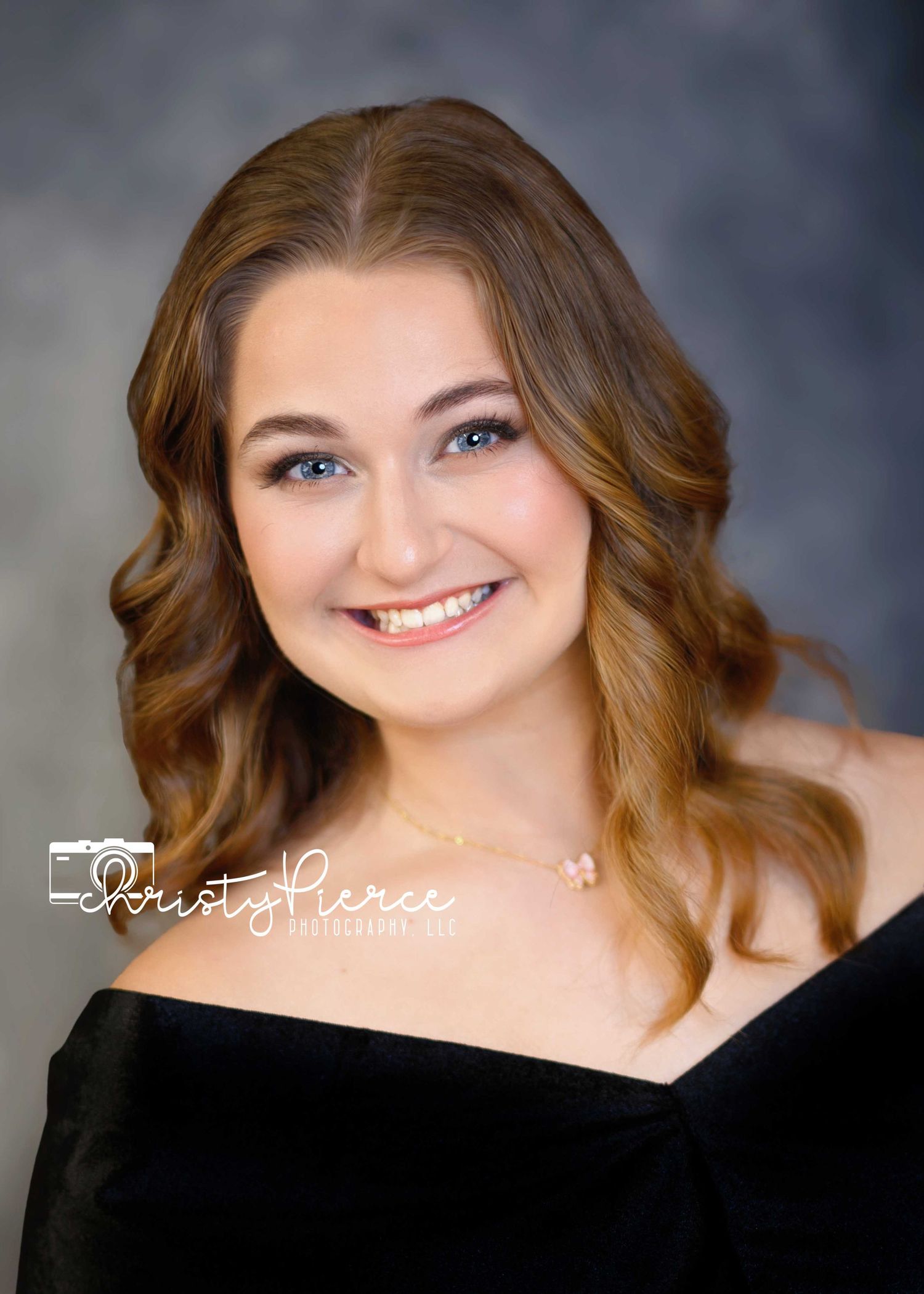 Professional headshot portrait with wavy brown hair and warm smile against dark background.