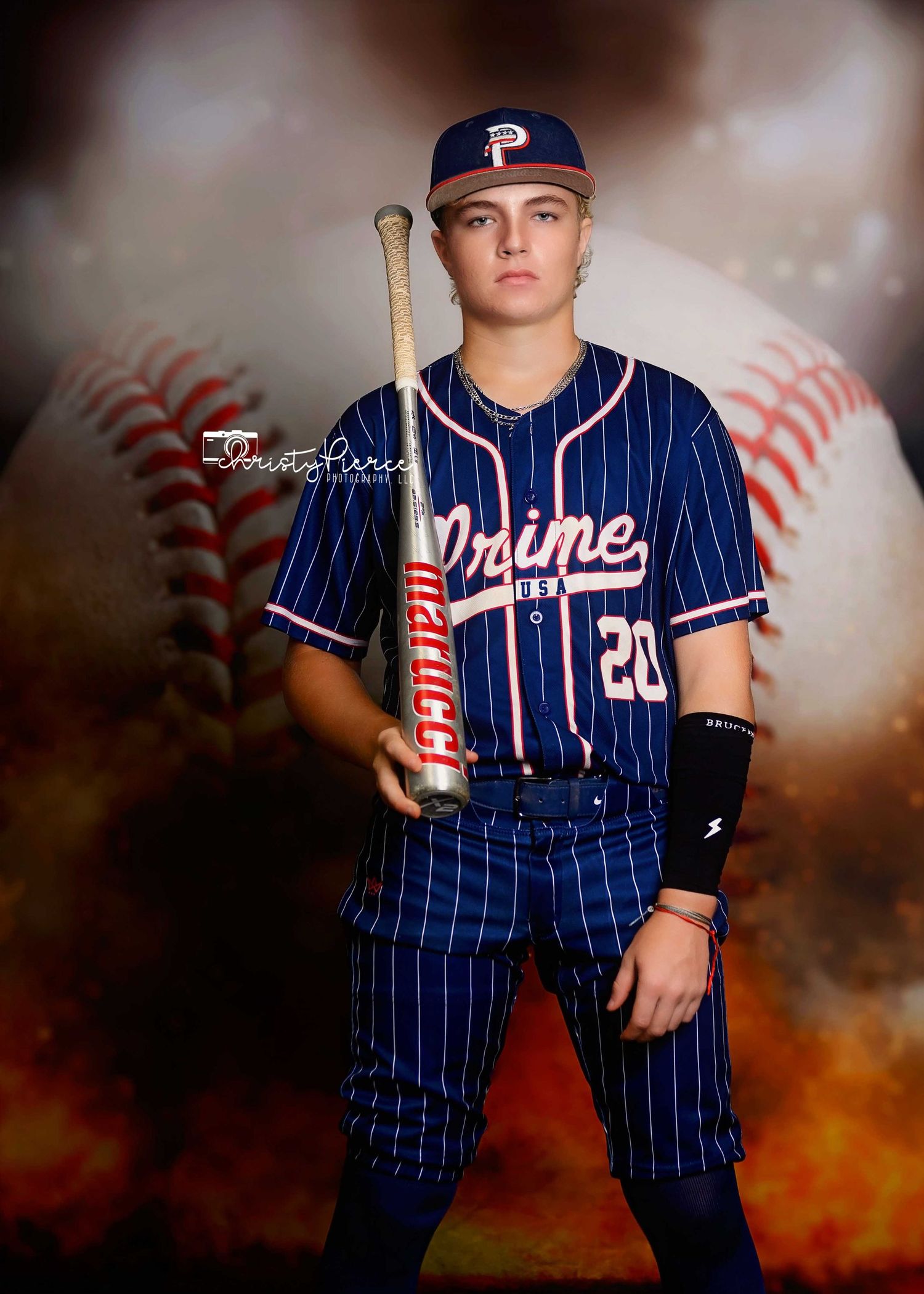 Baseball player in navy pinstriped uniform stands in dramatic lighting with orange smoky background effect.