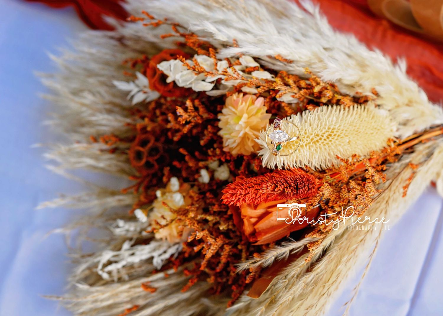 A collection of dried wheat stalks and preserved autumn flowers arranged in a natural bouquet.
