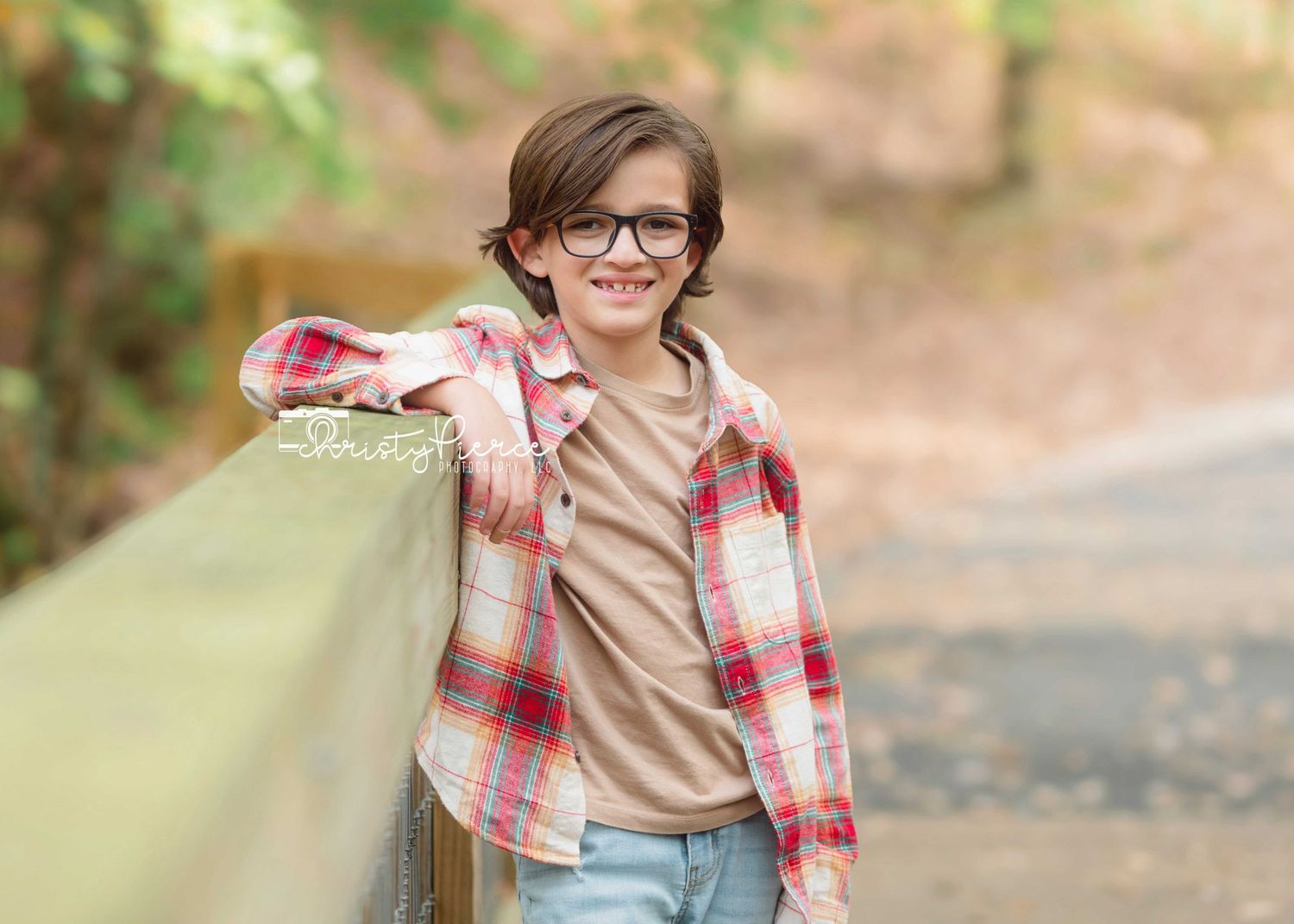 A person wearing glasses and plaid shirt carries a large beige shopping bag while walking outdoors on an autumn day.