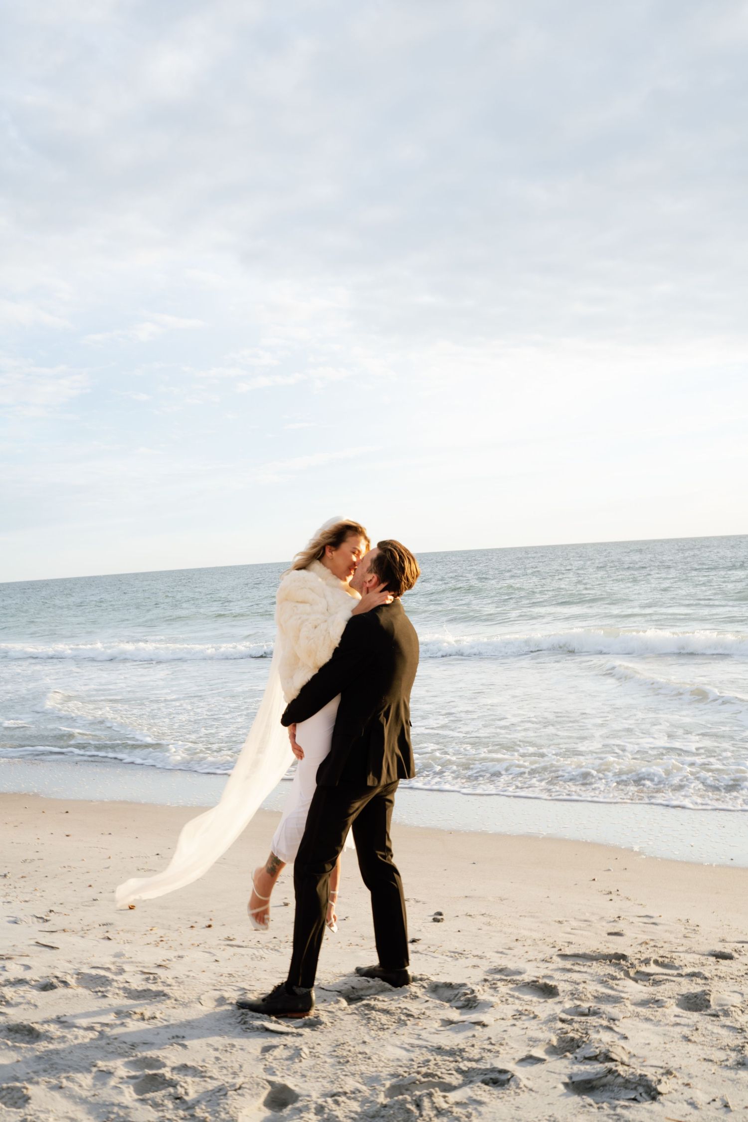 A romantic couple embraces on a sandy beach with ocean waves in the background across four sequential photos.