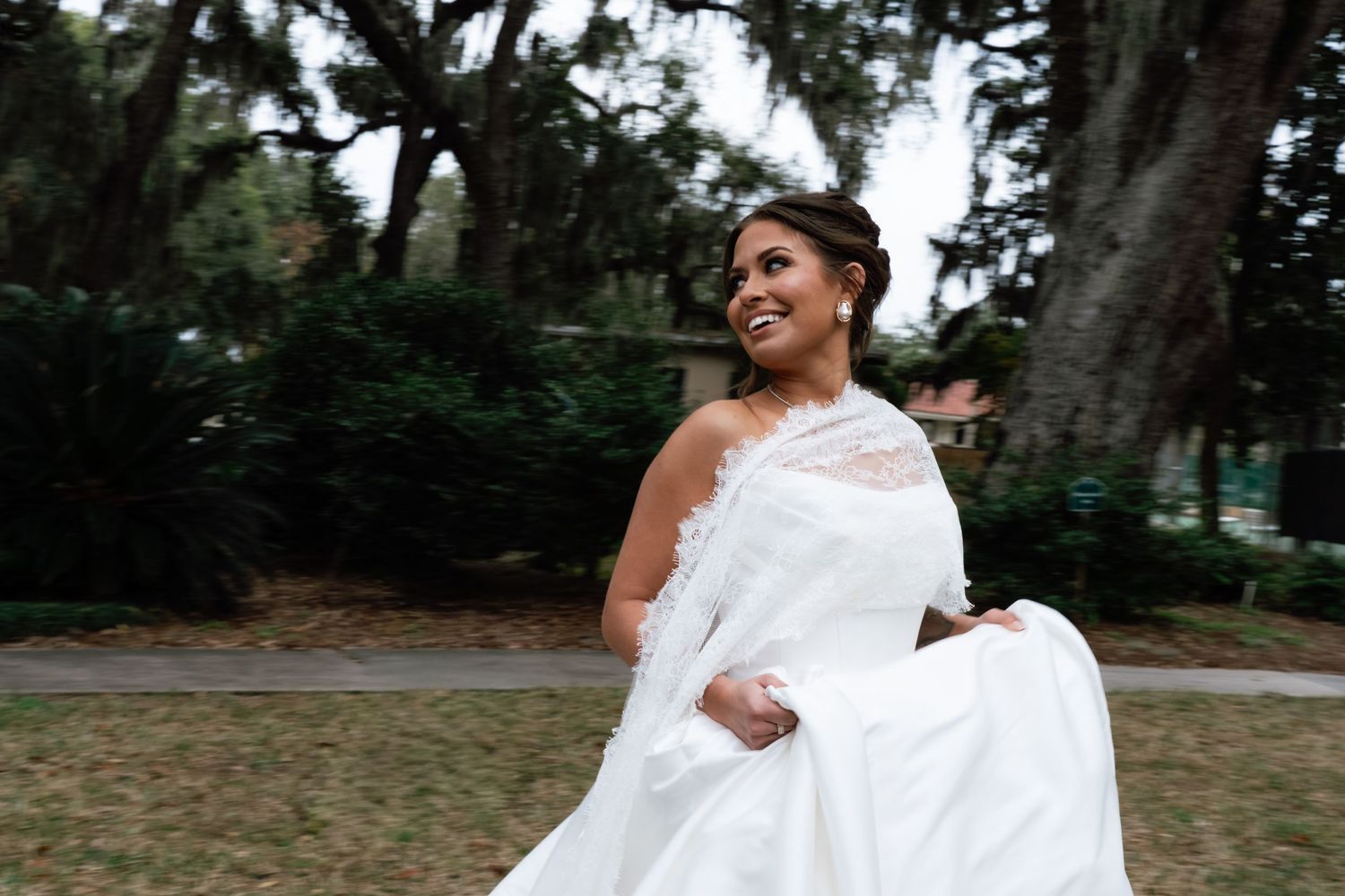 A joyful couple in wedding attire dances together in a garden setting during their celebration.