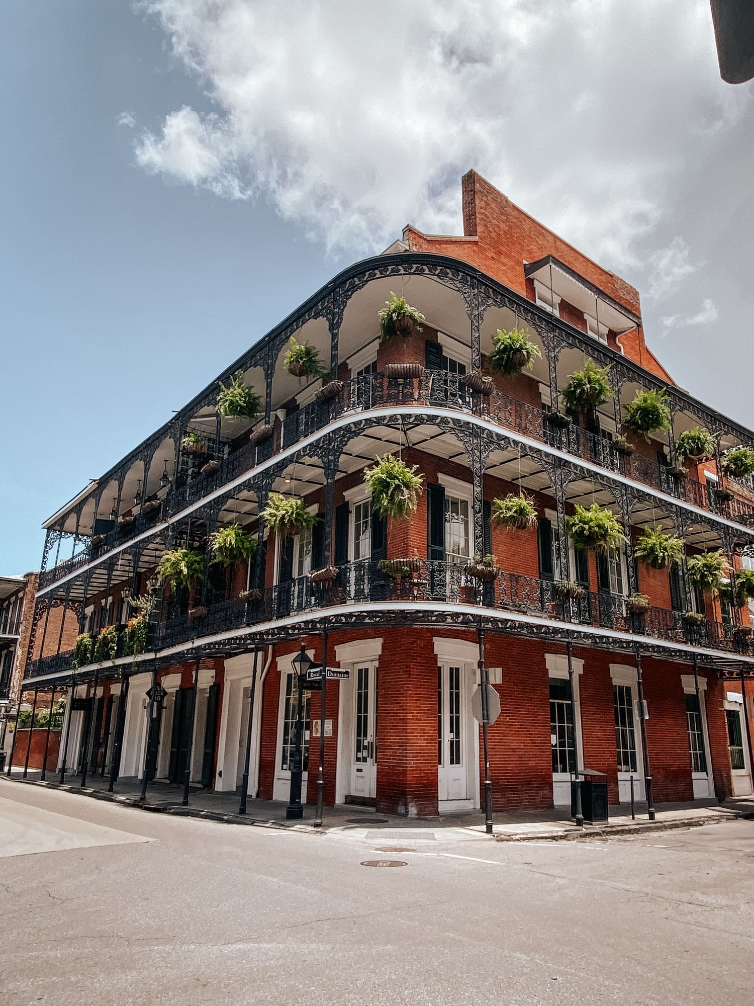 Historic buildings with wrought iron balconies line the corner of a street in New Orleans' French Quarter on a cloudy day.