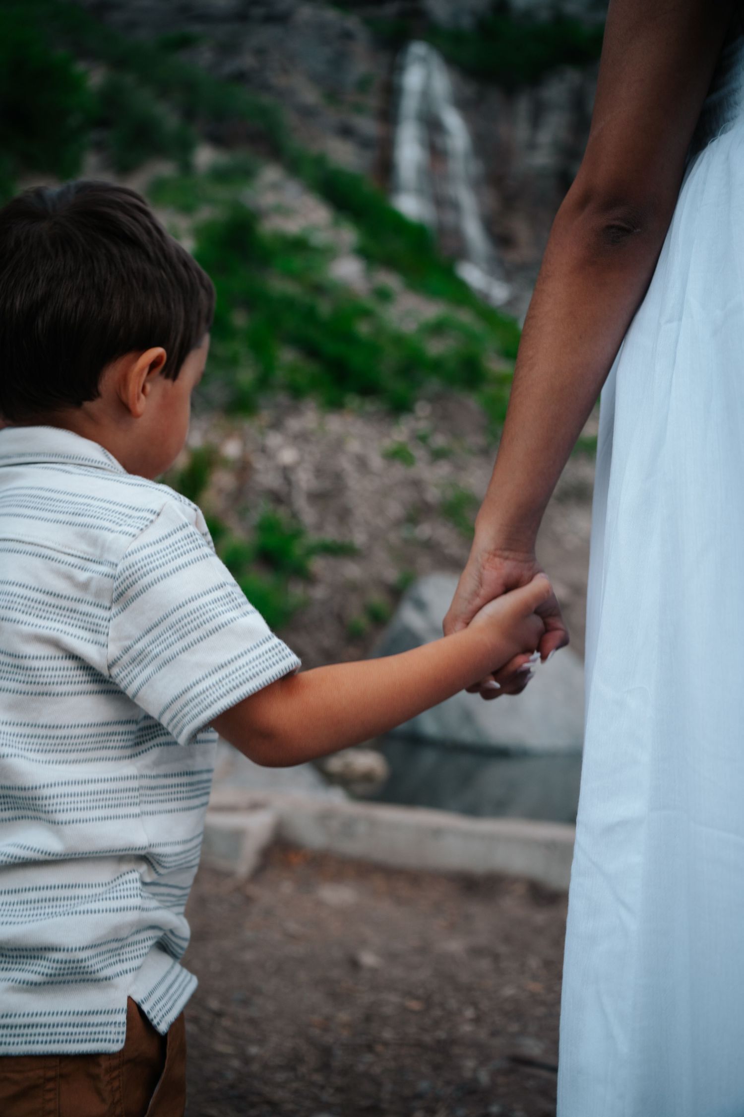 A person in a striped shirt reaches out to touch a white surface against a blurred outdoor background.