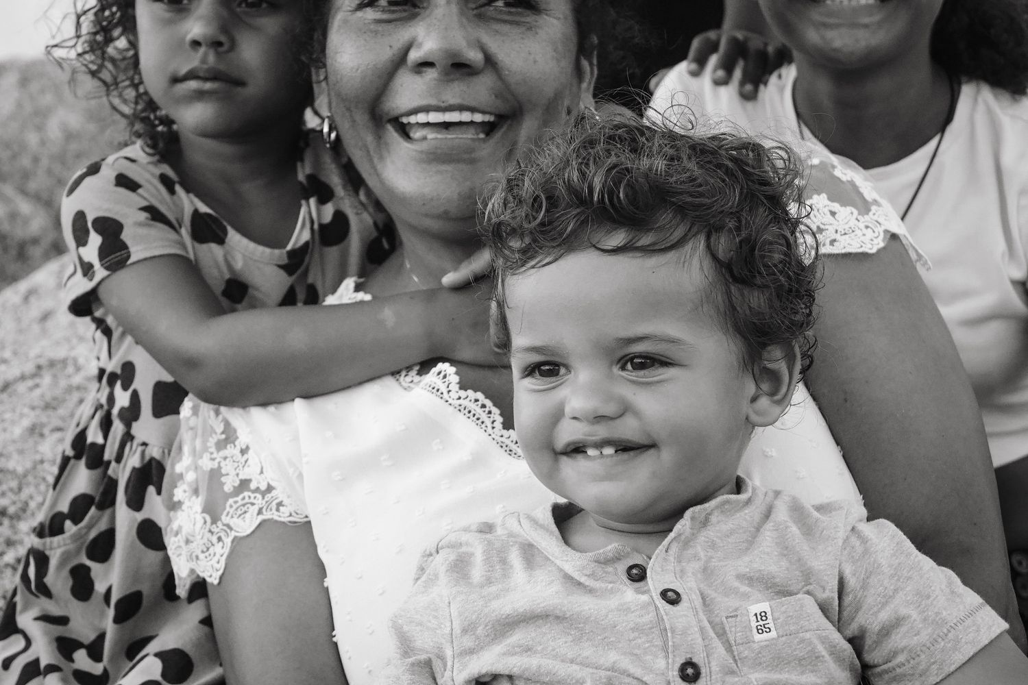 Black and white portrait of a multi-generational family group sharing smiles.
