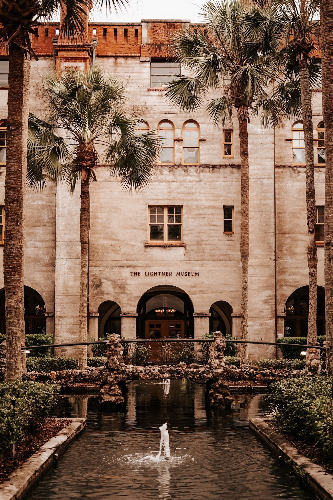 Historic Lightner Museum entrance in St. Augustine with palm trees and fountain in Mediterranean-style courtyard.