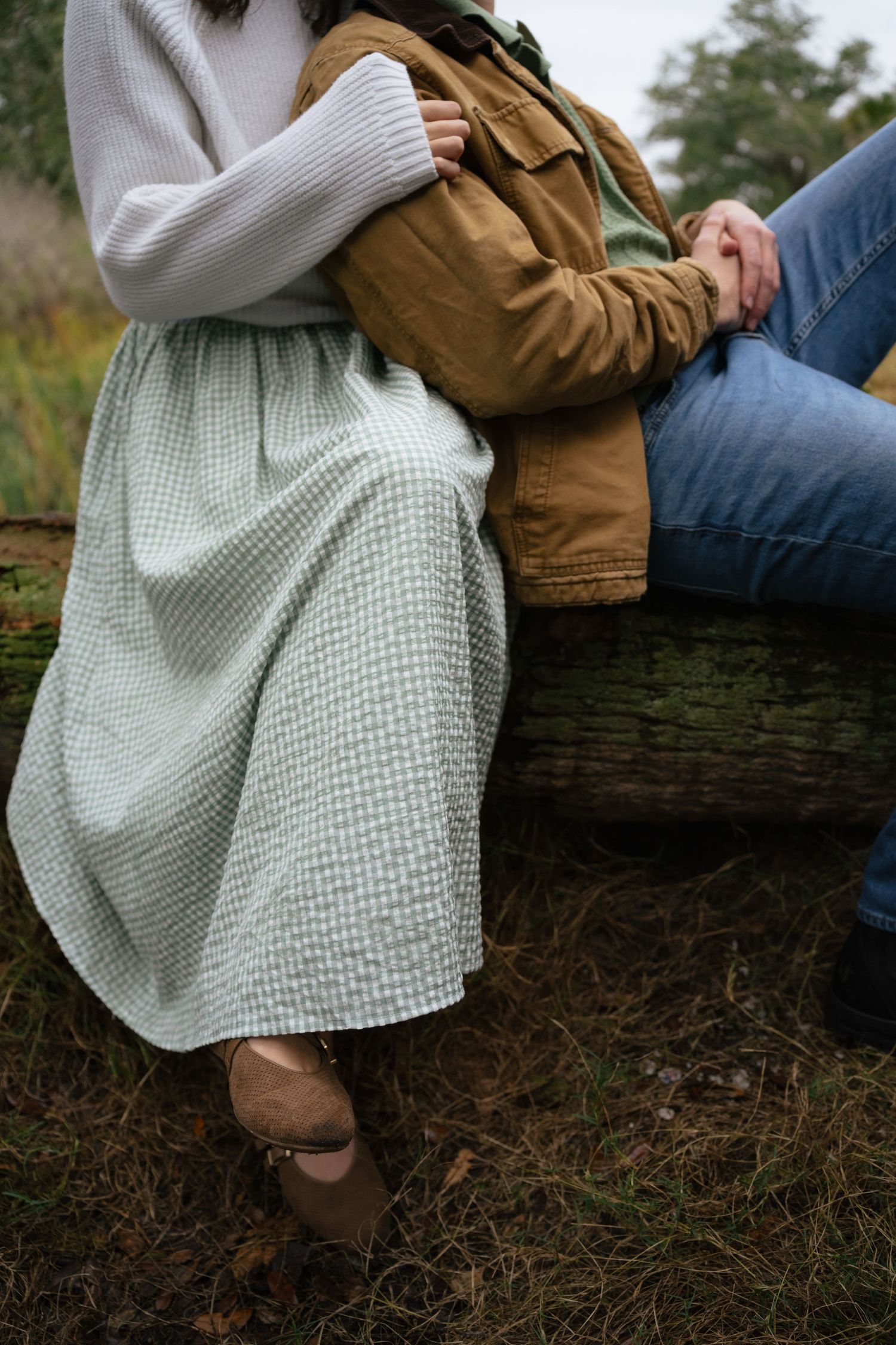 A person in a white sweater and brown jacket sits on a fallen log in nature, shown from different angles.