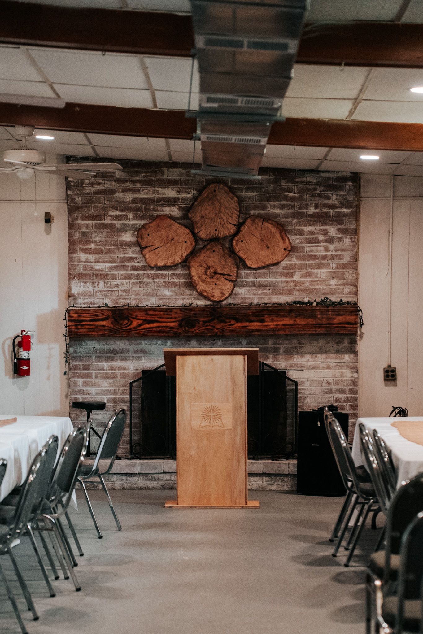 Interior view of event space with exposed brick wall, wooden podium, and decorative wall art featuring rustic wooden accents.