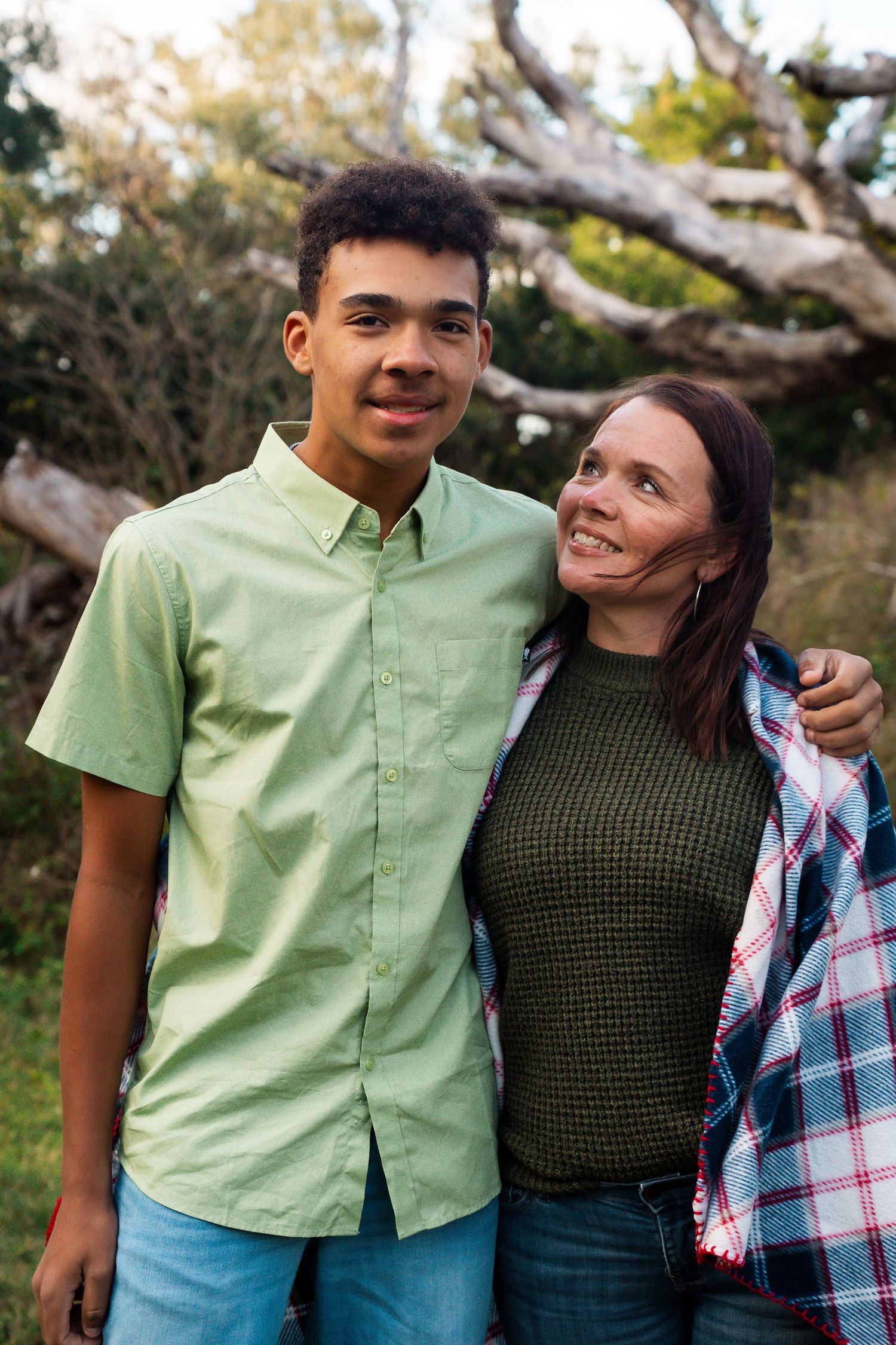 Close-up outdoor portrait of two people smiling together in a natural setting.