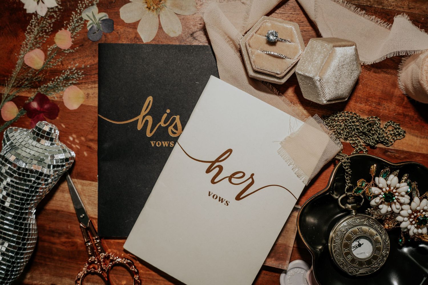 Vintage wedding stationery and decorative elements arranged artistically with flowers and calligraphy on a rustic wooden surface.