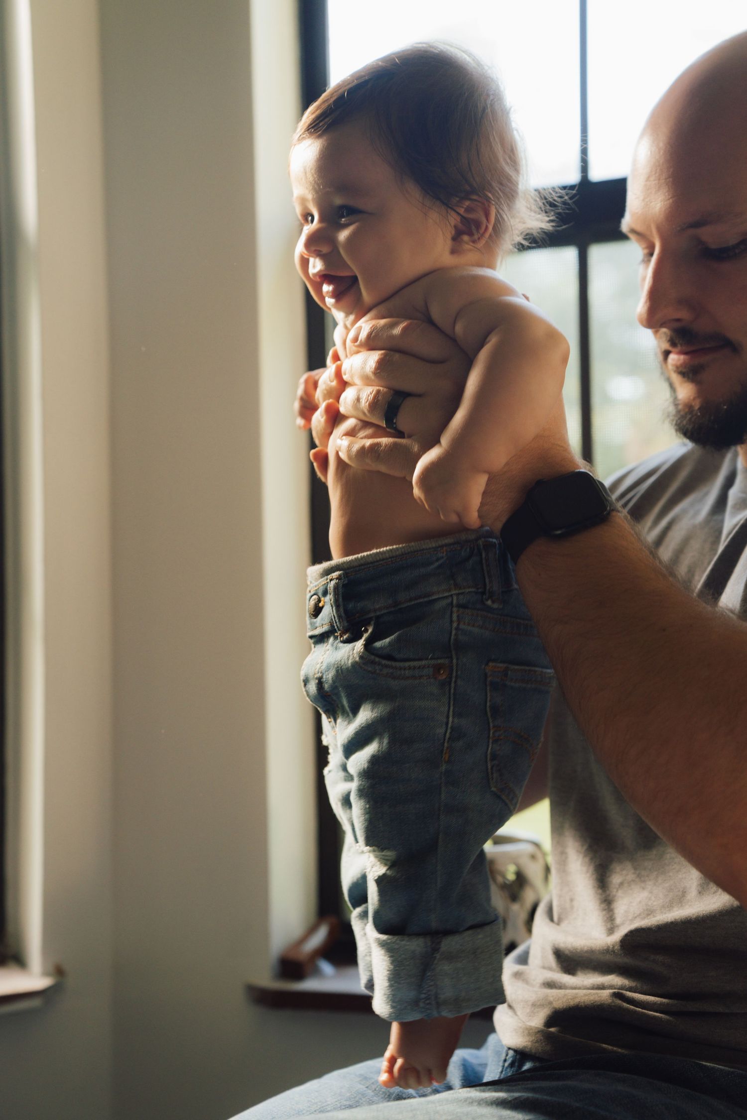 A series of candid moments showing a baby in denim overalls being held near a window with natural light.