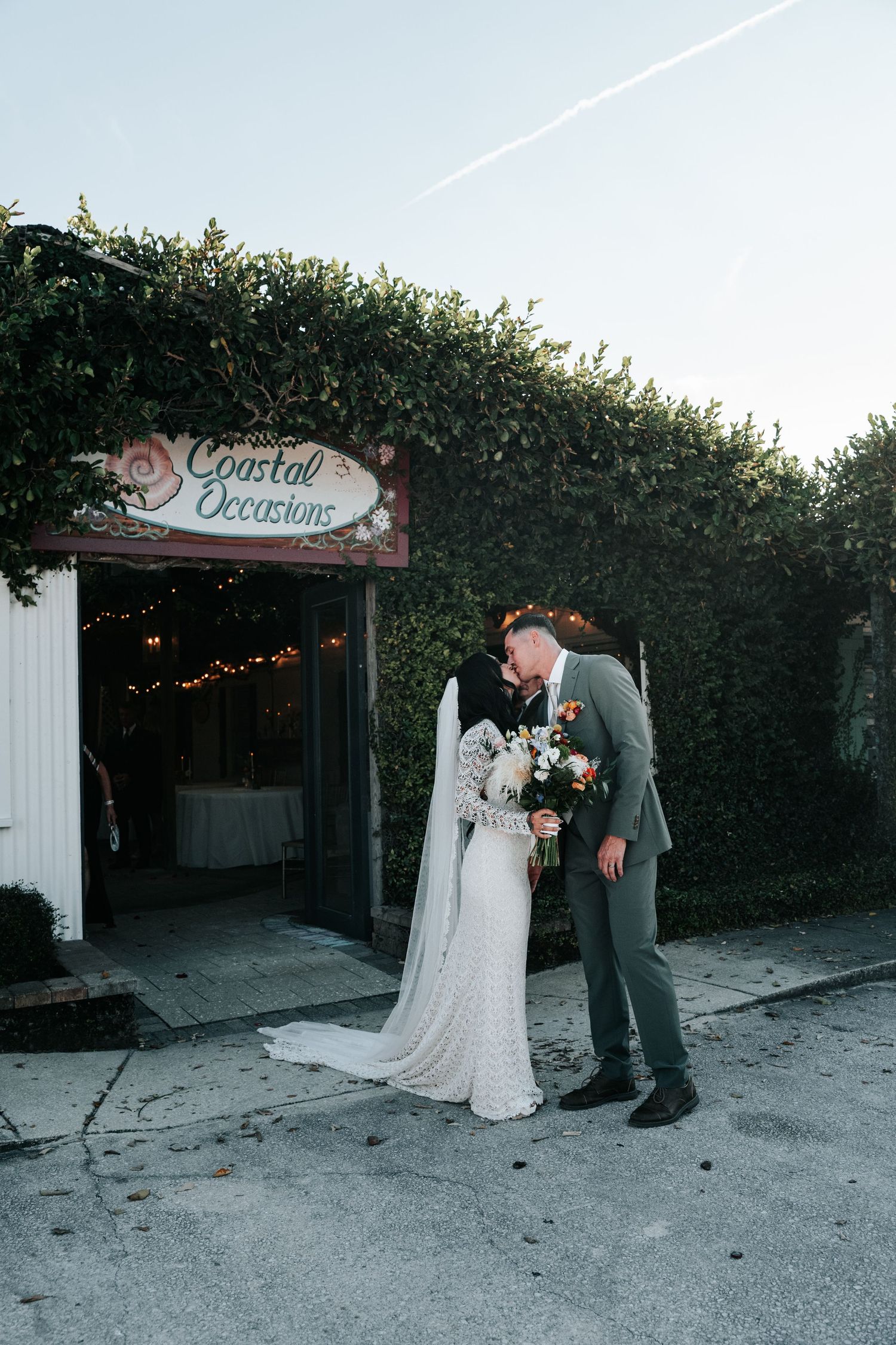 A romantic wedding moment outside the Crystal Occasions venue with a decorated entrance archway and greenery.