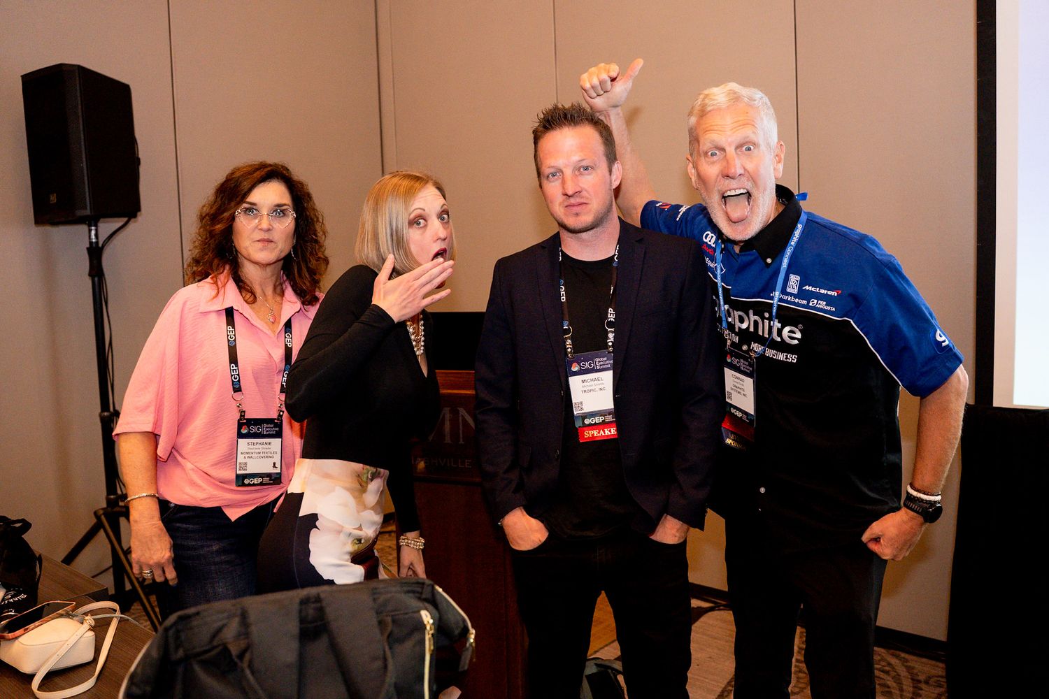 Four people pose playfully together at a professional conference event.