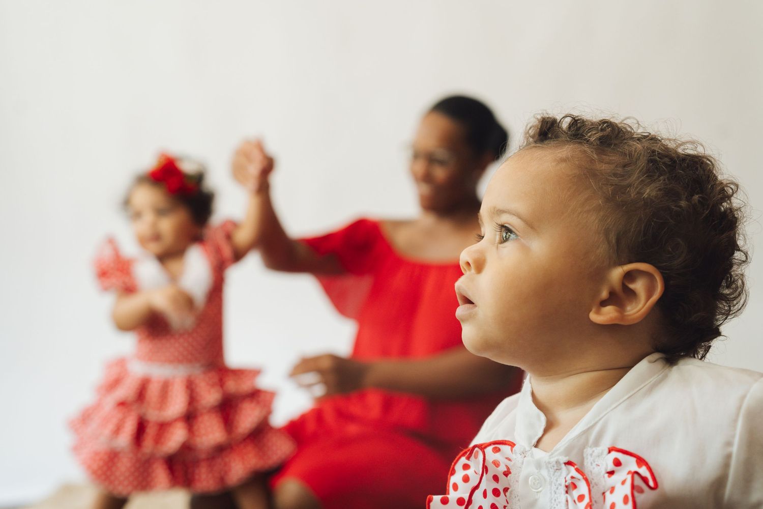 A series of candid portrait photos showing children in red and white holiday outfits against a light background.