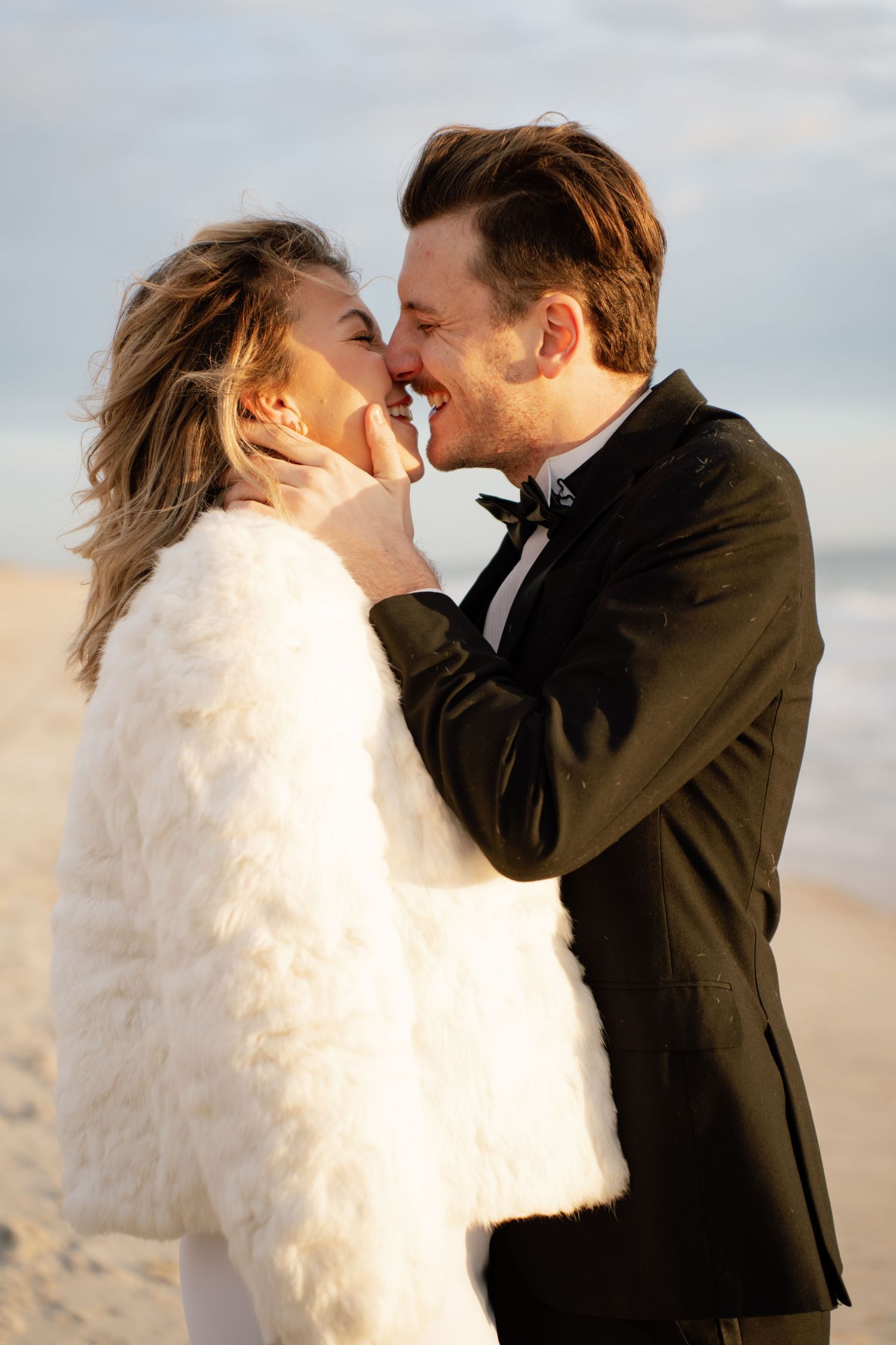 A romantic couple in wedding attire share intimate kisses on a beach at sunset in a series of candid photos.