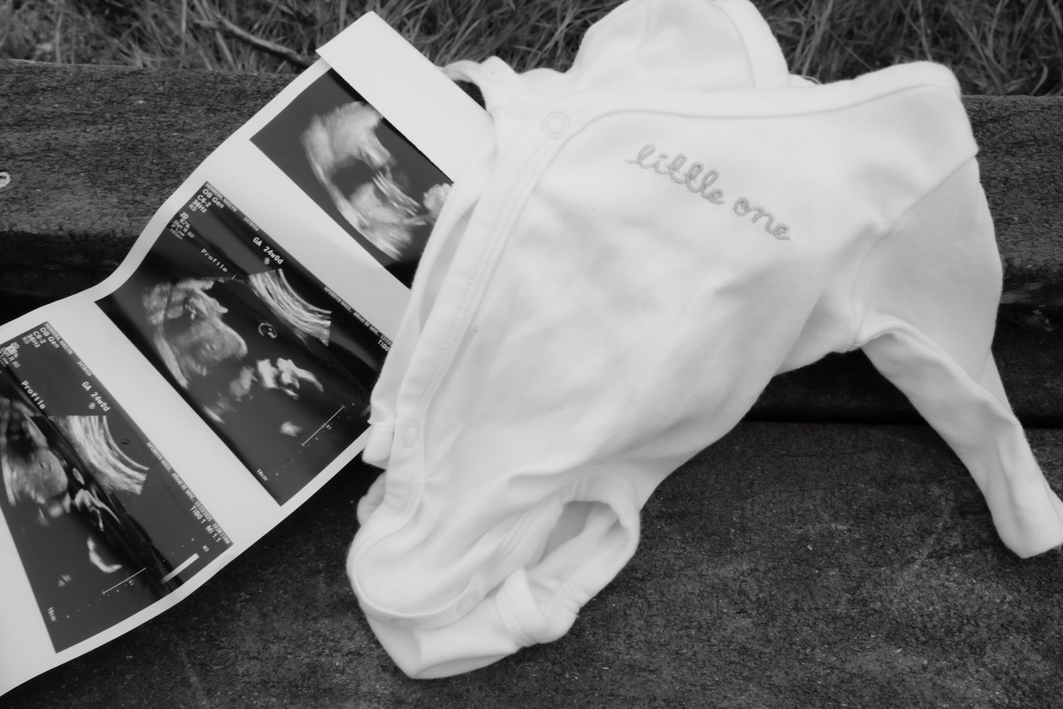 Black and white photographs scattered on ground with white fabric or paper creating an artistic composition.