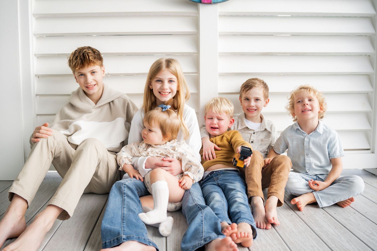 Children and pets sitting together on white porch steps for a casual portrait.