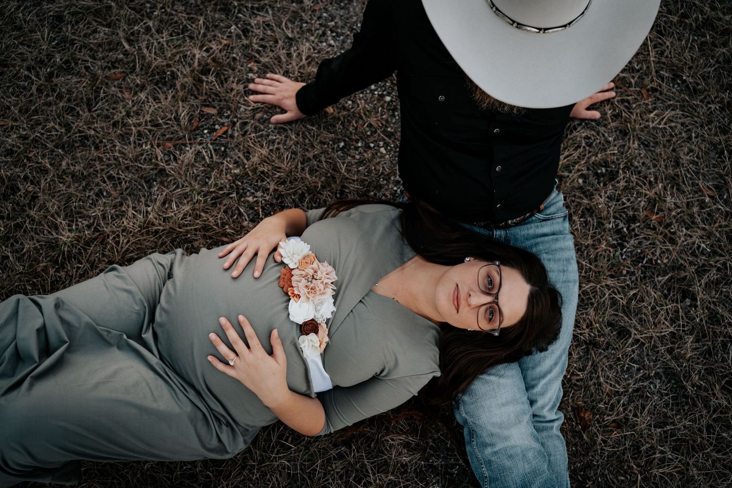 Overhead maternity portrait of couple with flowers on grass.