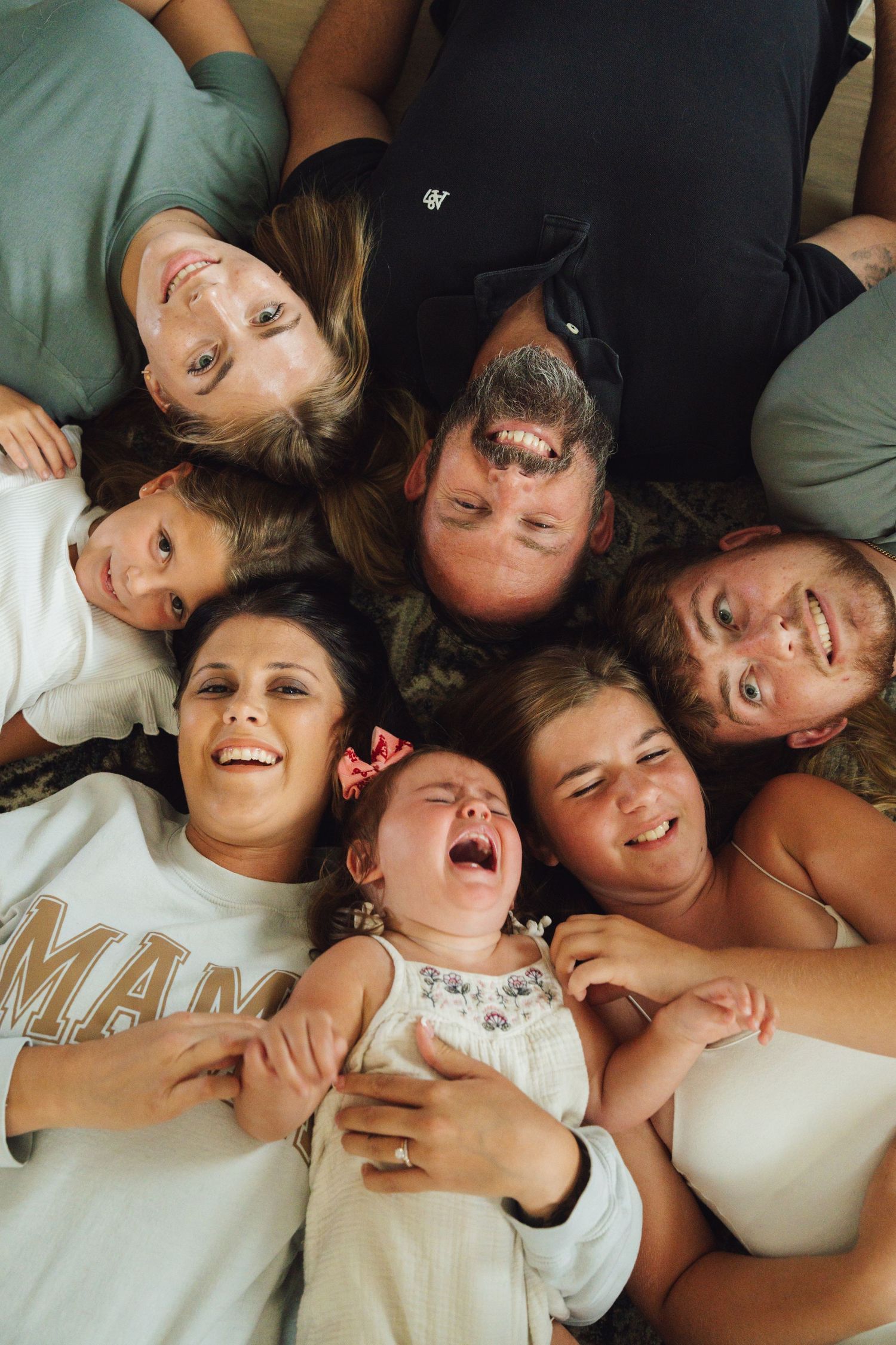 A joyful group photo showing people lying down together and laughing with genuine expressions of happiness.