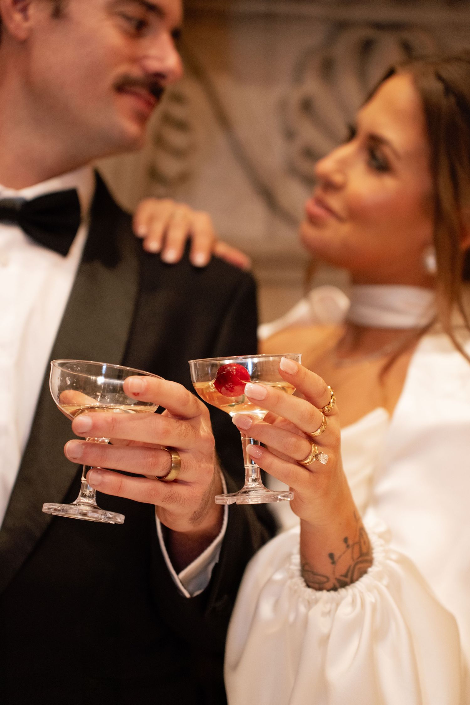 Two people in formal attire clink champagne glasses together in an elegant toast at a celebration.