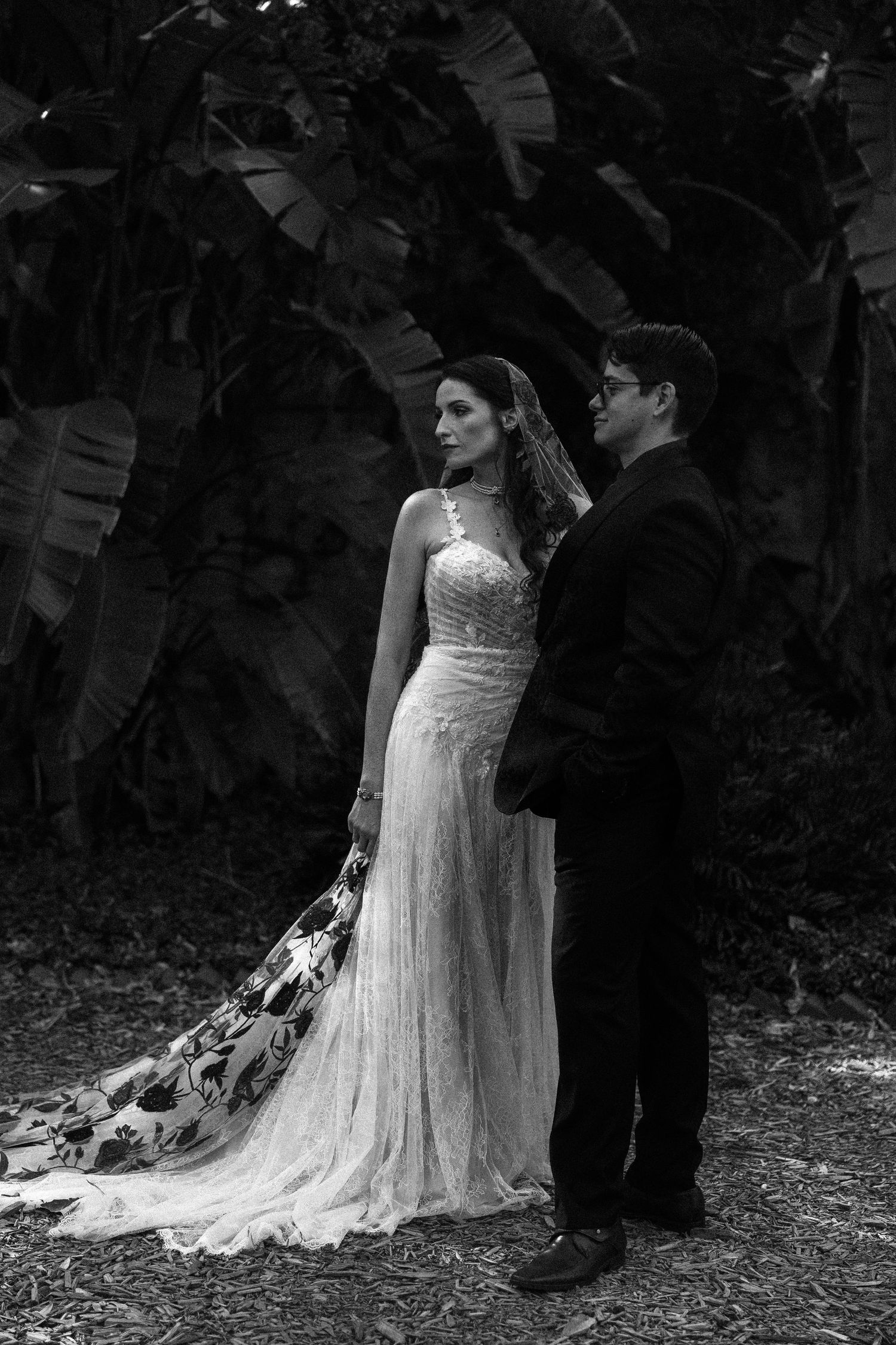 Black and white wedding photo series showing couple in elegant dress and suit dancing together in a garden setting.