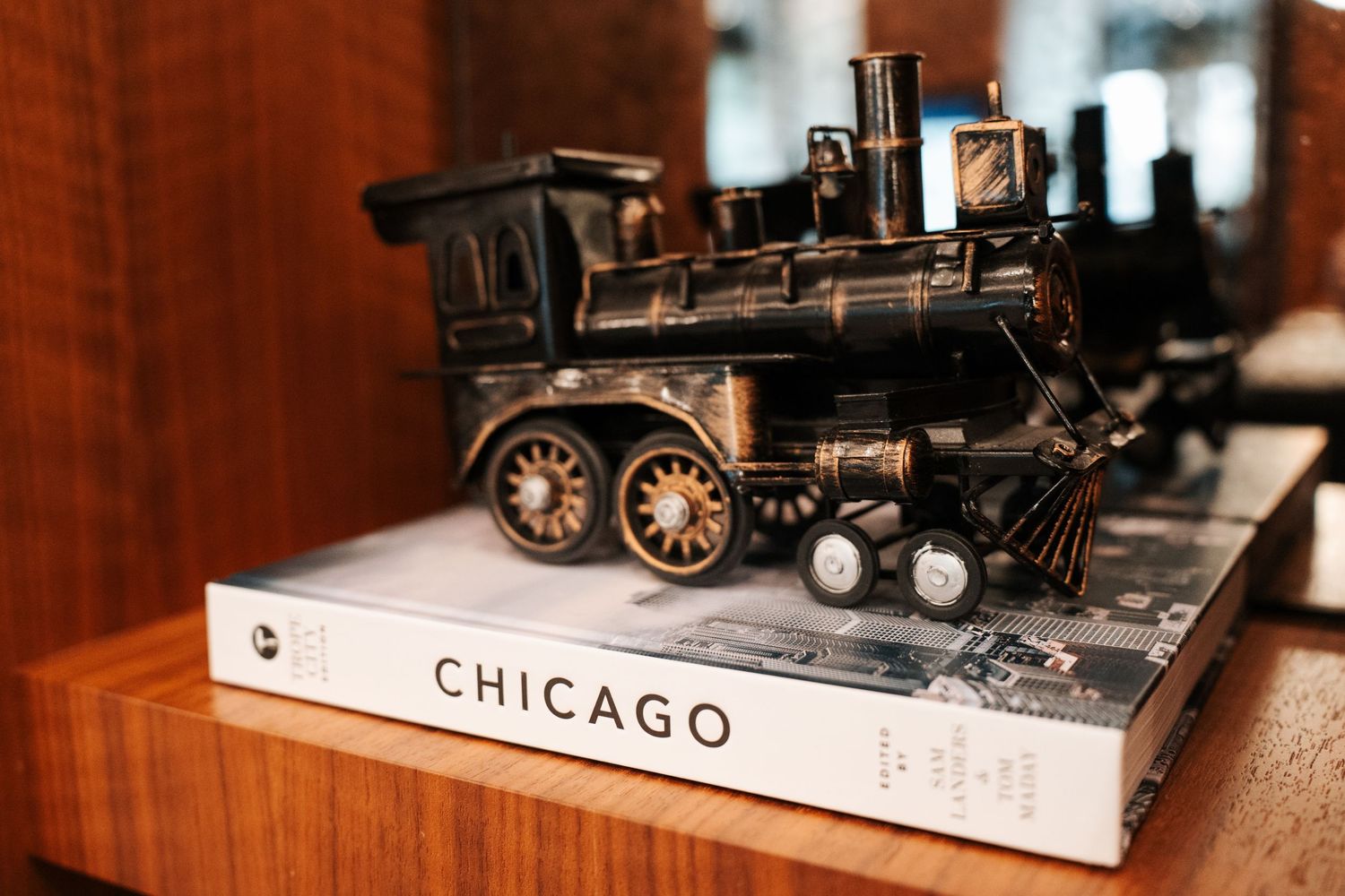 Vintage black metal locomotive model displayed on a Chicago coffee table book on a wooden shelf.