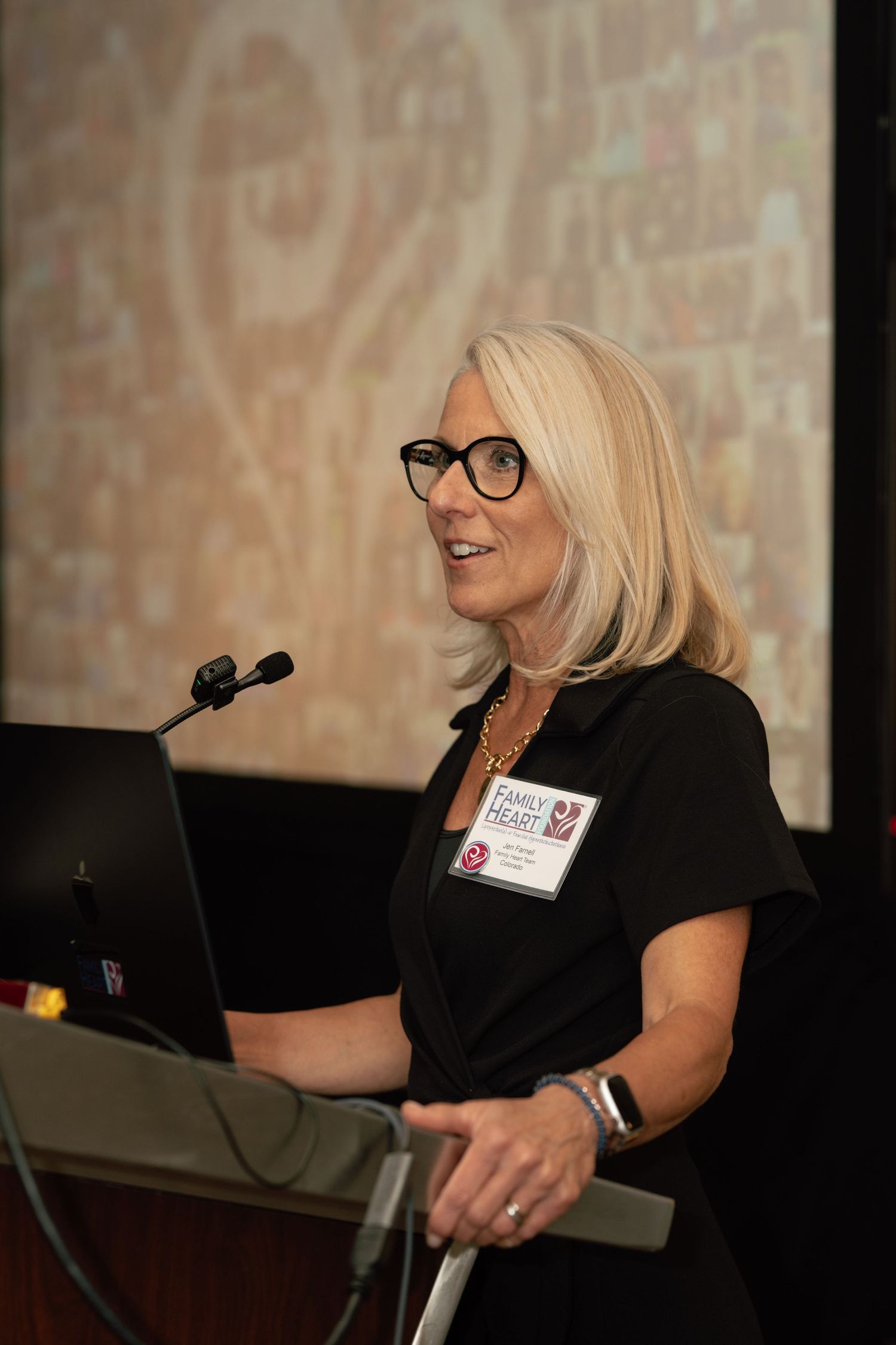 Woman with blonde hair and glasses speaks at podium during Family Ready conference presentation.
