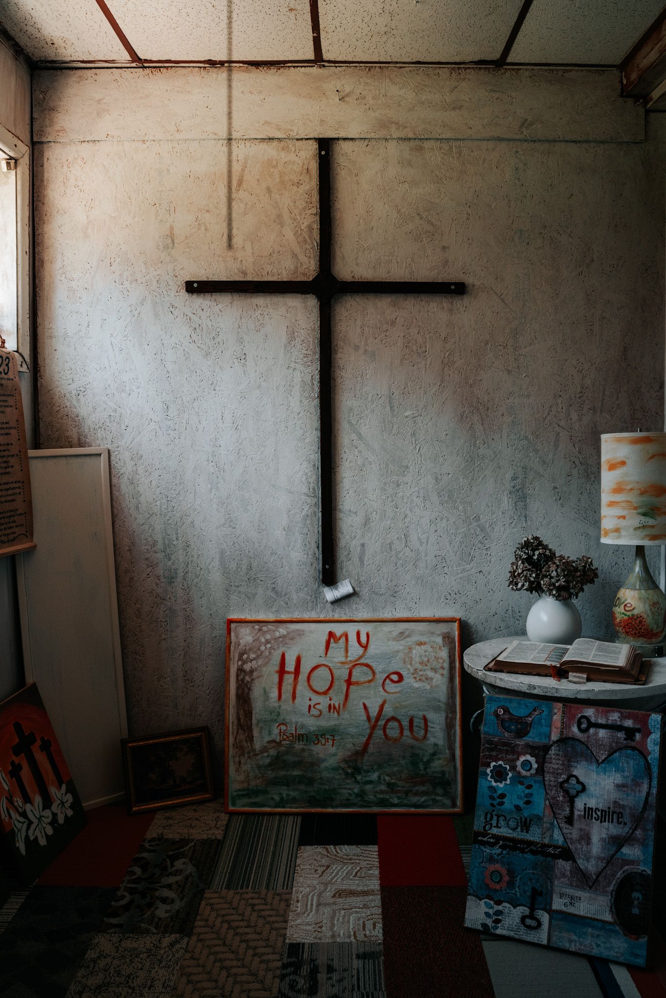 A dark religious room with a black cross on the wall and a sign reading 