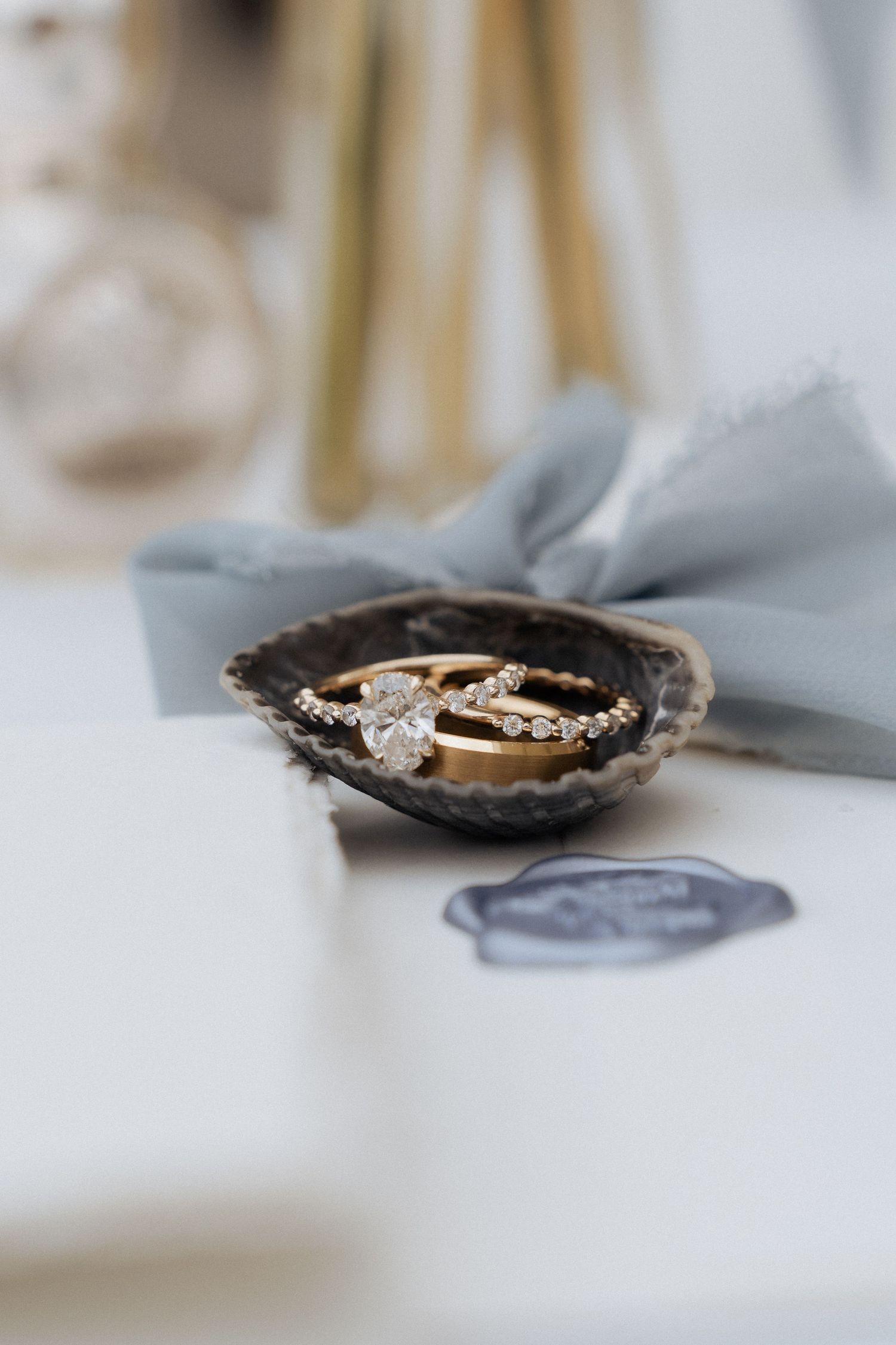 A delicate gold engagement ring with diamond accents sits in a black velvet box on a white surface.