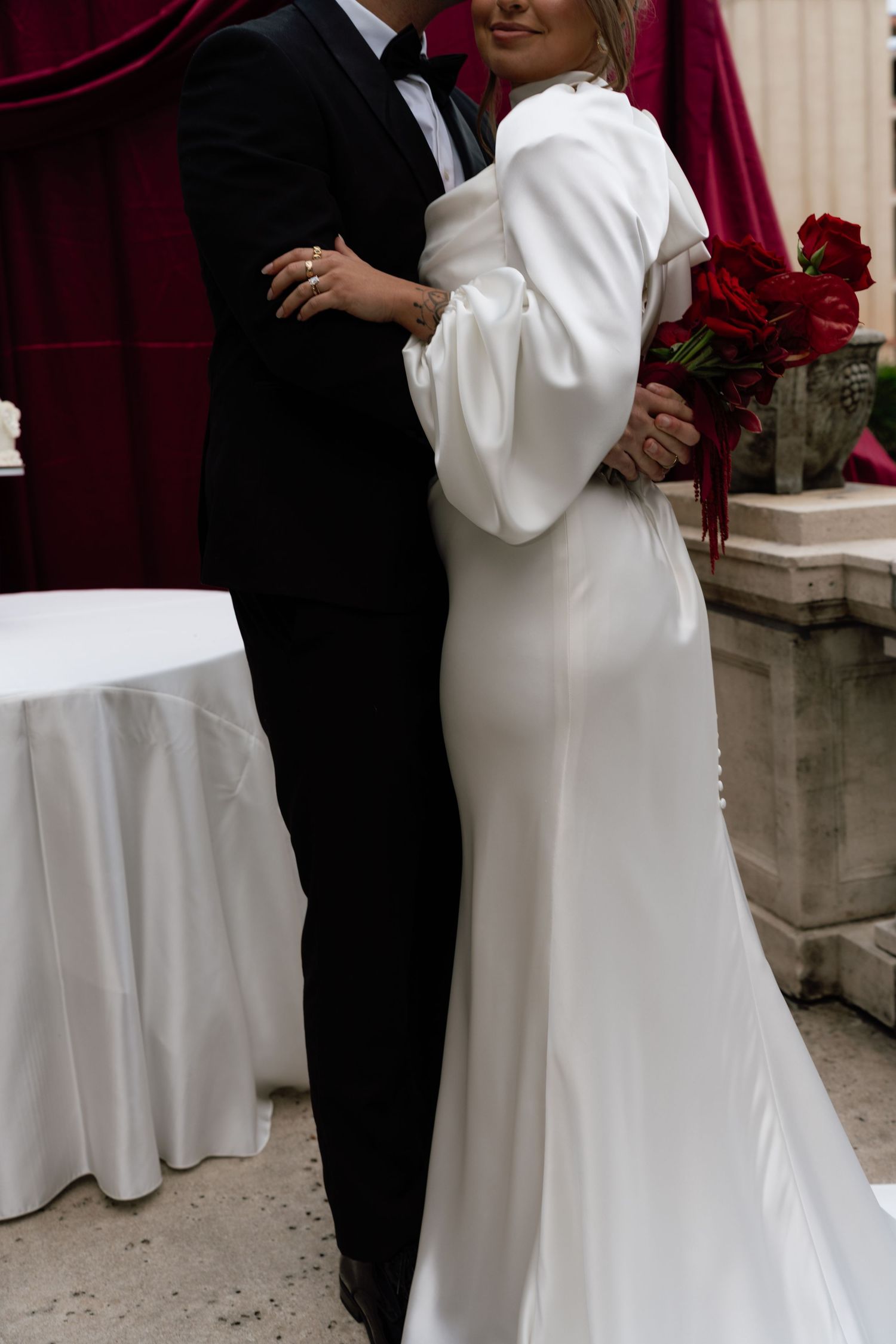 A bride in a white dress and groom in black tuxedo dance together during their wedding celebration.