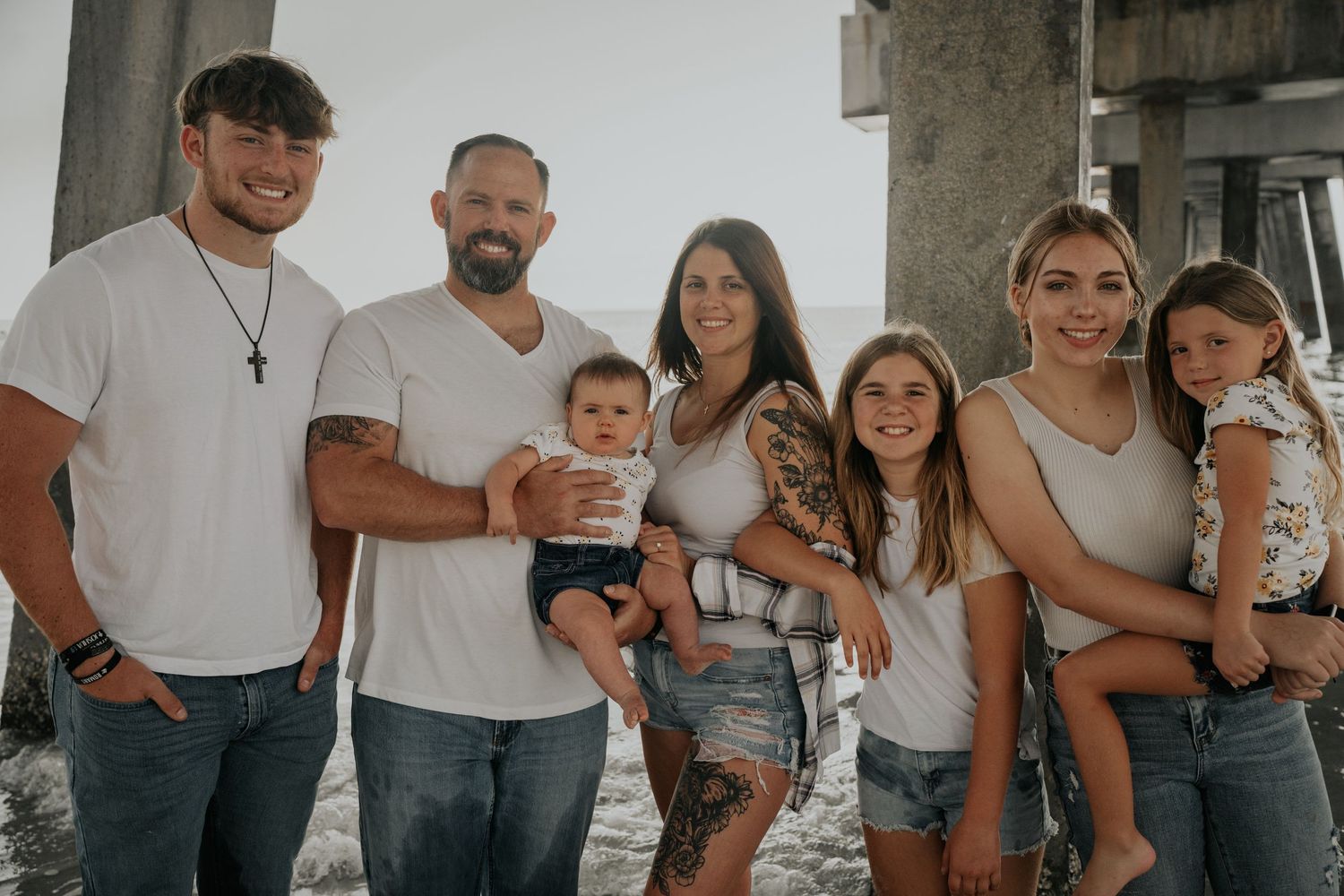 Extended family group in casual attire poses together outdoors in natural lighting.
