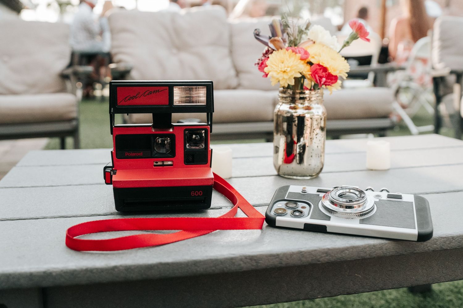 A vintage red Polaroid instant camera with a carrying strap sits on a gray surface in natural lighting.
